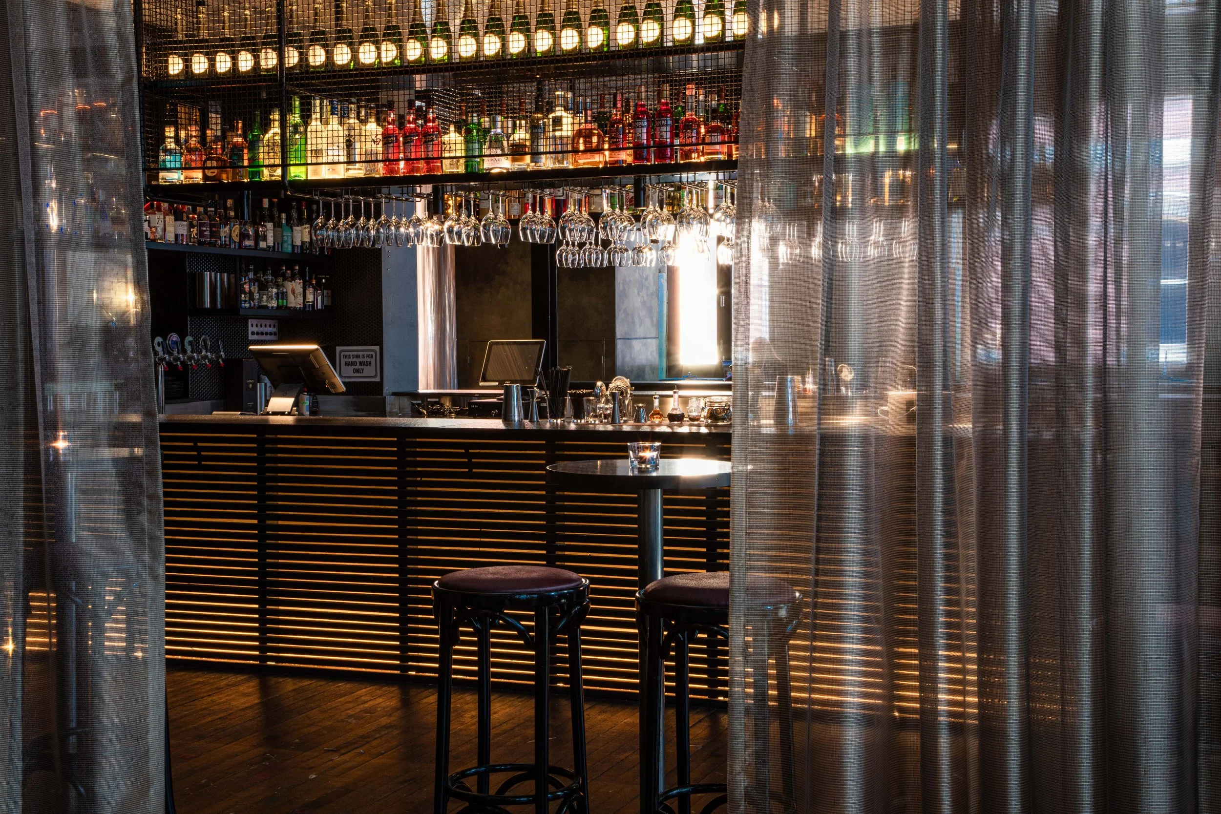 	
Longsong bar with hanging glasses, bottles of liquor on shelves.