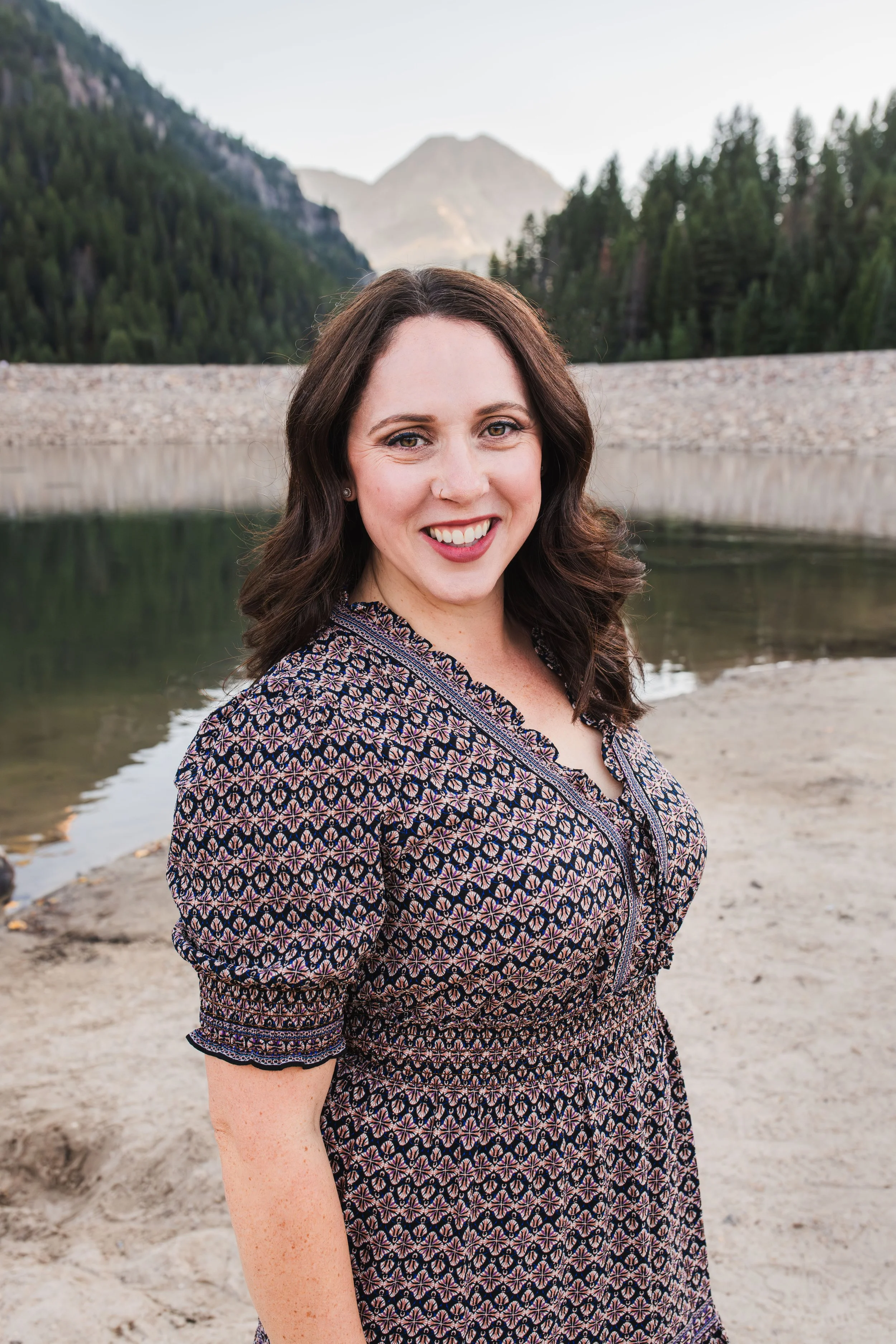 Ghostwriter Katie Ludlow Rich wearing a dress, standing in front of a mountain resevoir