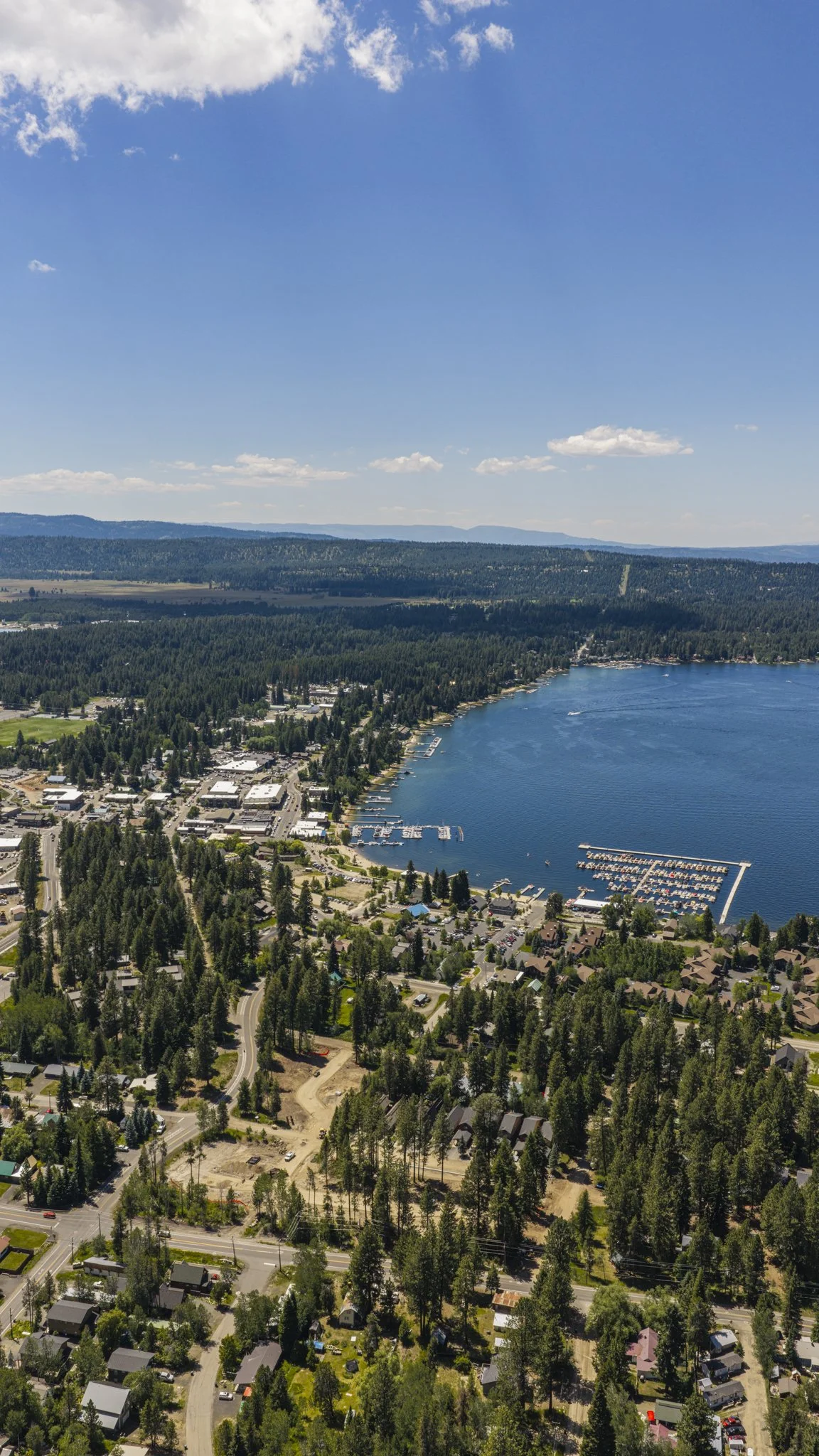 Aerial view of a snow-covered downtown McCall near a frozen Lake Payette, with streets, trees, charming buildings, and mountains in the background.