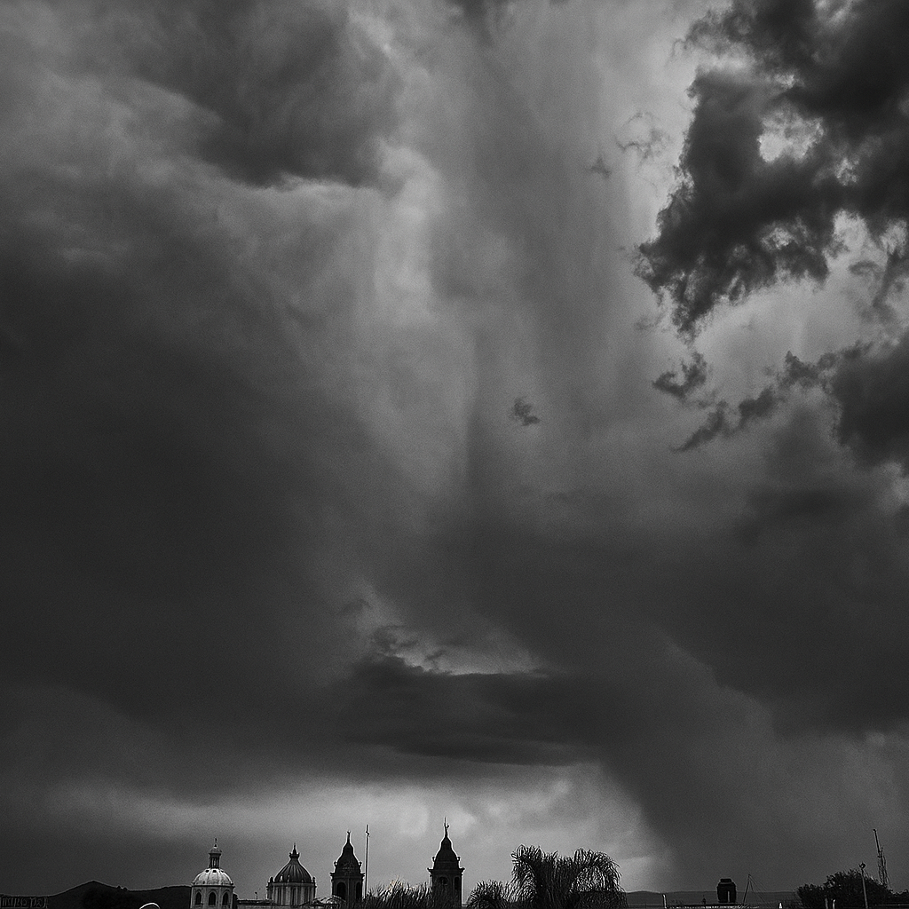 Cielo nublado oscuro con nubes torcidas y densas, vista del horizonte con algunas estructuras y árboles en primer plano