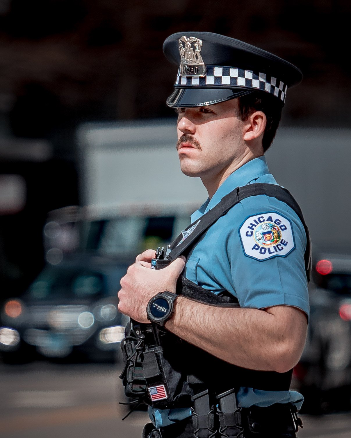 A Chicago police officer wearing a uniform, badge, and hat, standing outdoors with a serious expression.