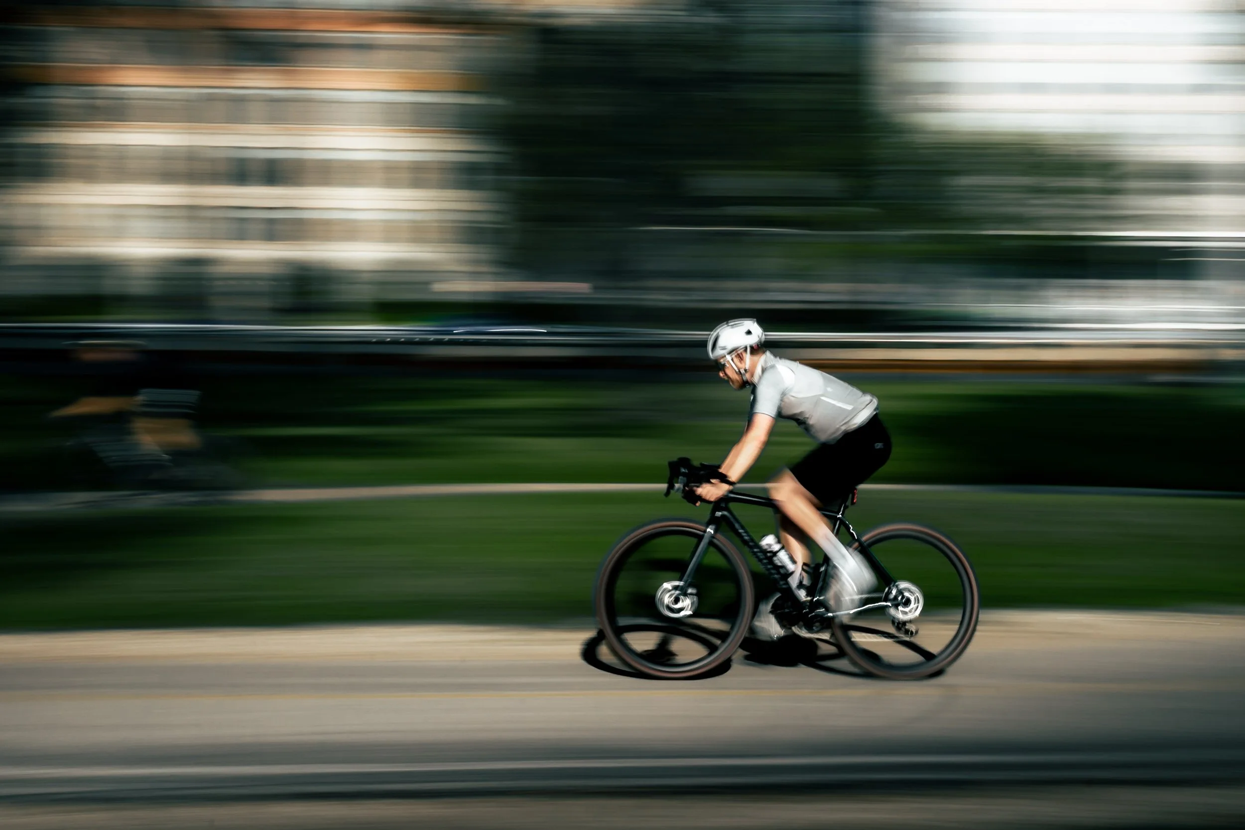 A person riding a bicycle at high speed on a paved road, with a blurred background indicating motion.