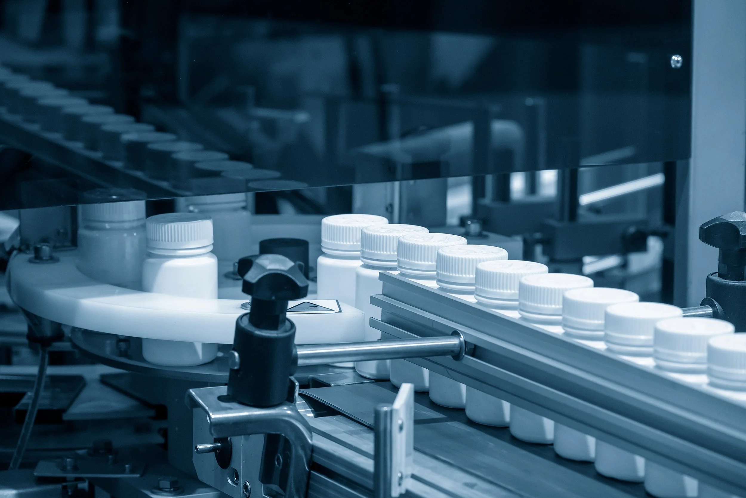 Pharmaceutical bottles on an industrial assembly line in a manufacturing facility.