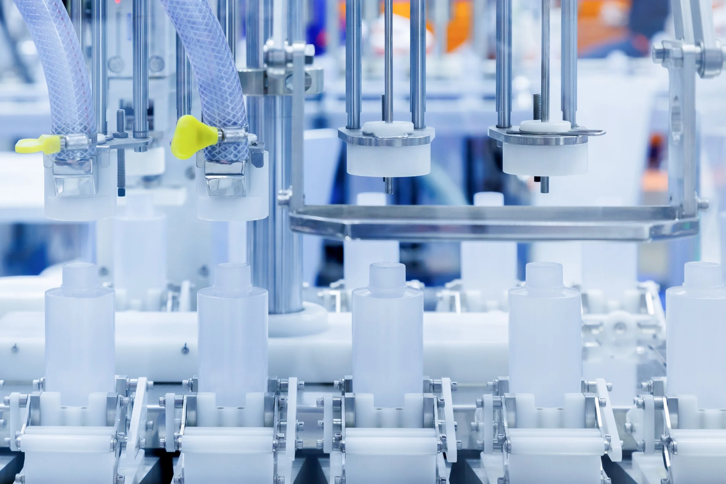 Industrial machinery and filling bottles in a pharmaceutical or cosmetic manufacturing plant.