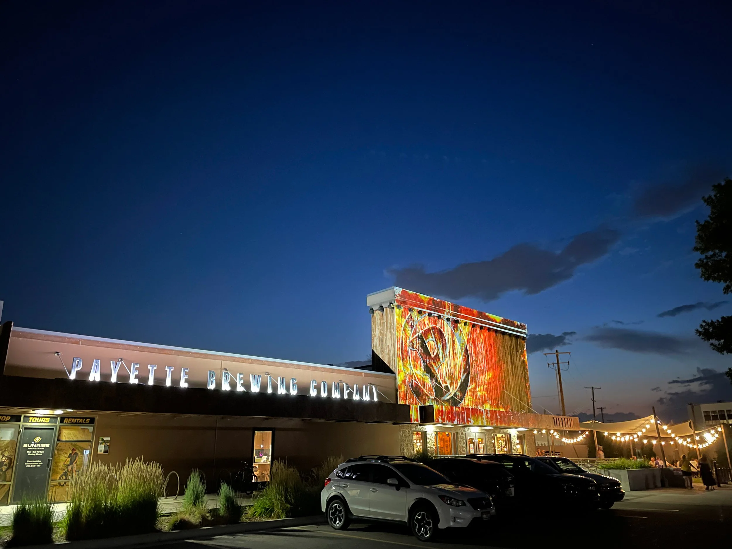 Payette Brewing Company taproom in Boise with fiery projection mapped logo, channel letter sign lit at left.