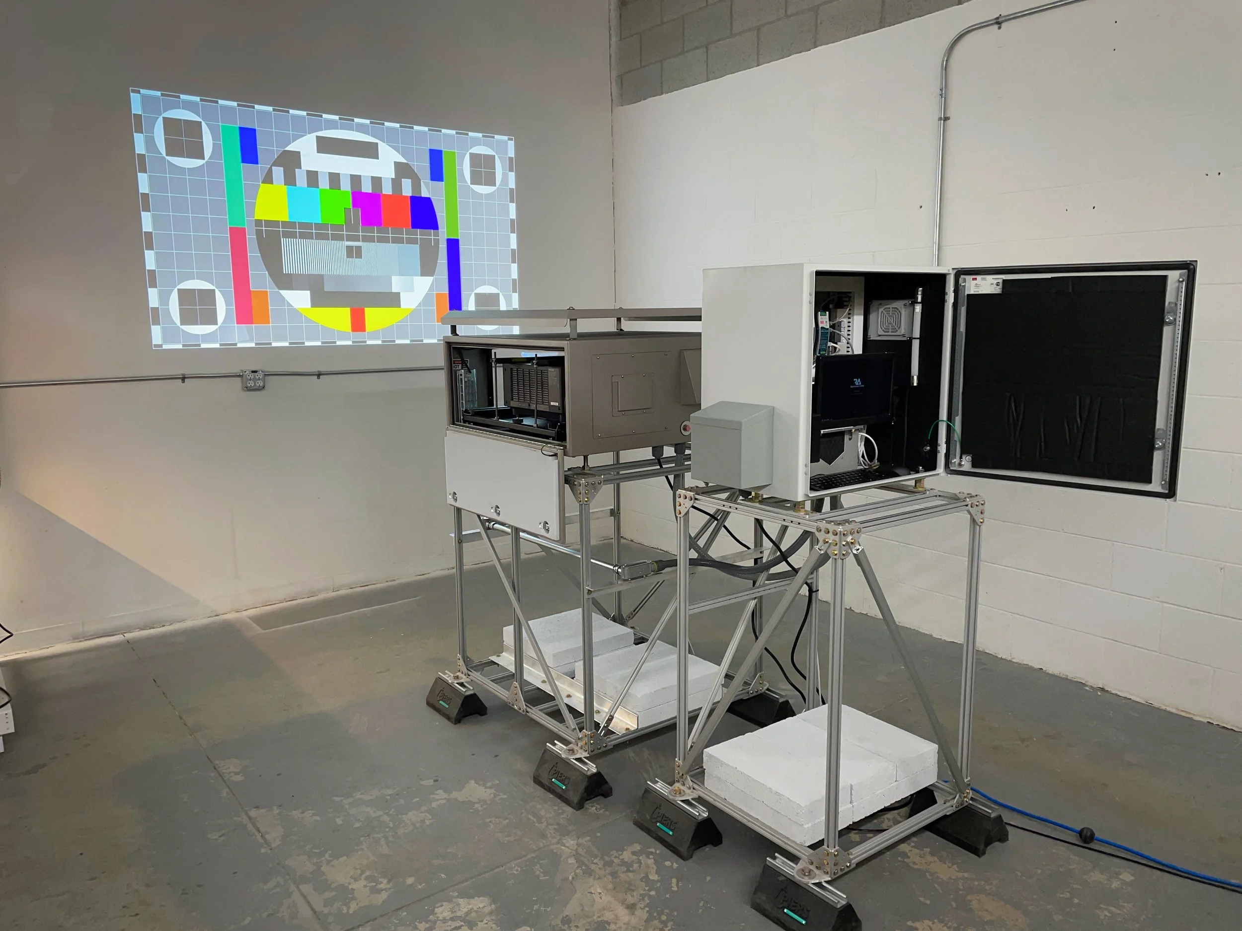 Projection mapping system on a custom aluminum rig in a warehouse, projecting a color test pattern onto the wall