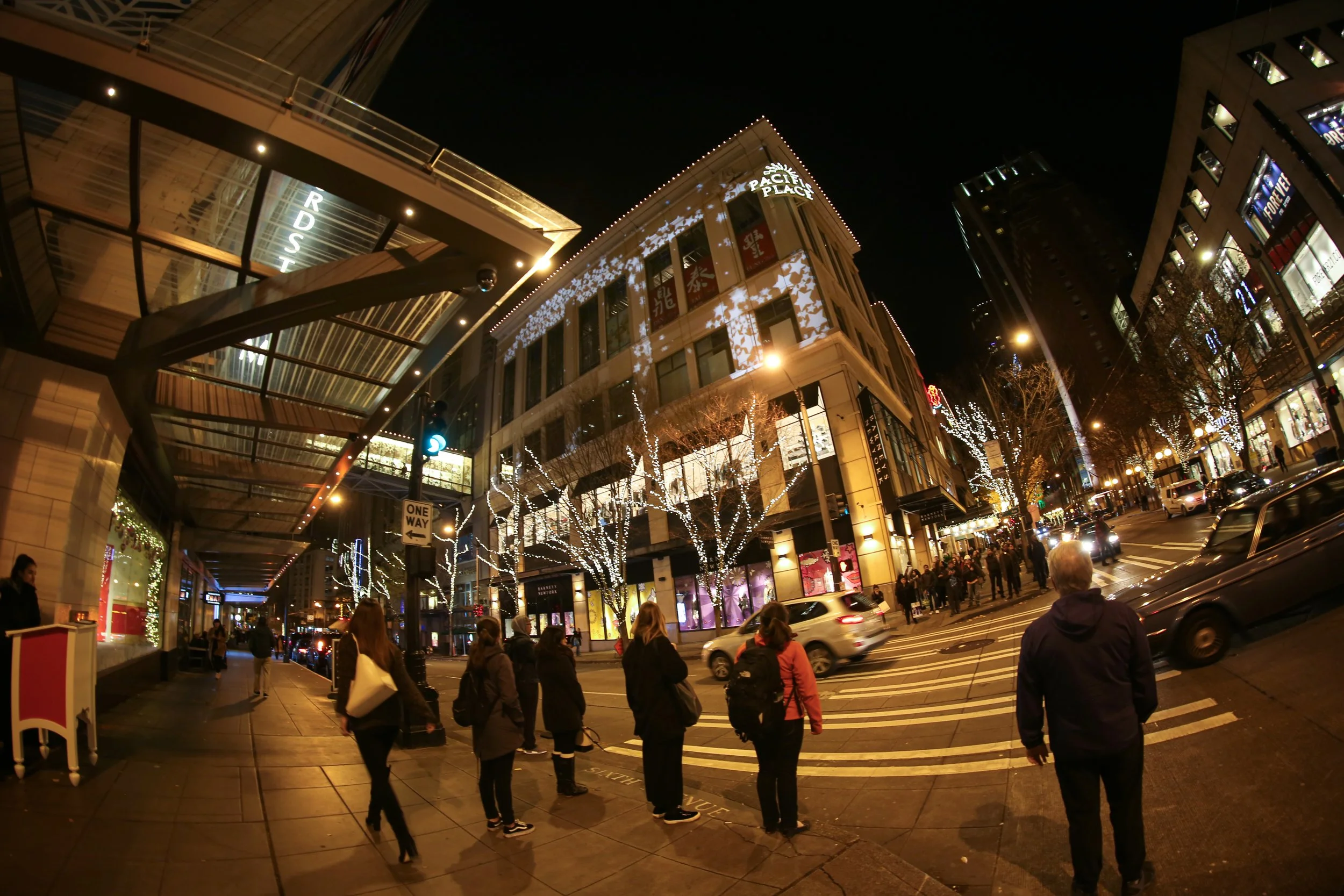 Pacific Place holiday projection mapping, downtown Seattle, passersby on the corner watching the lit building