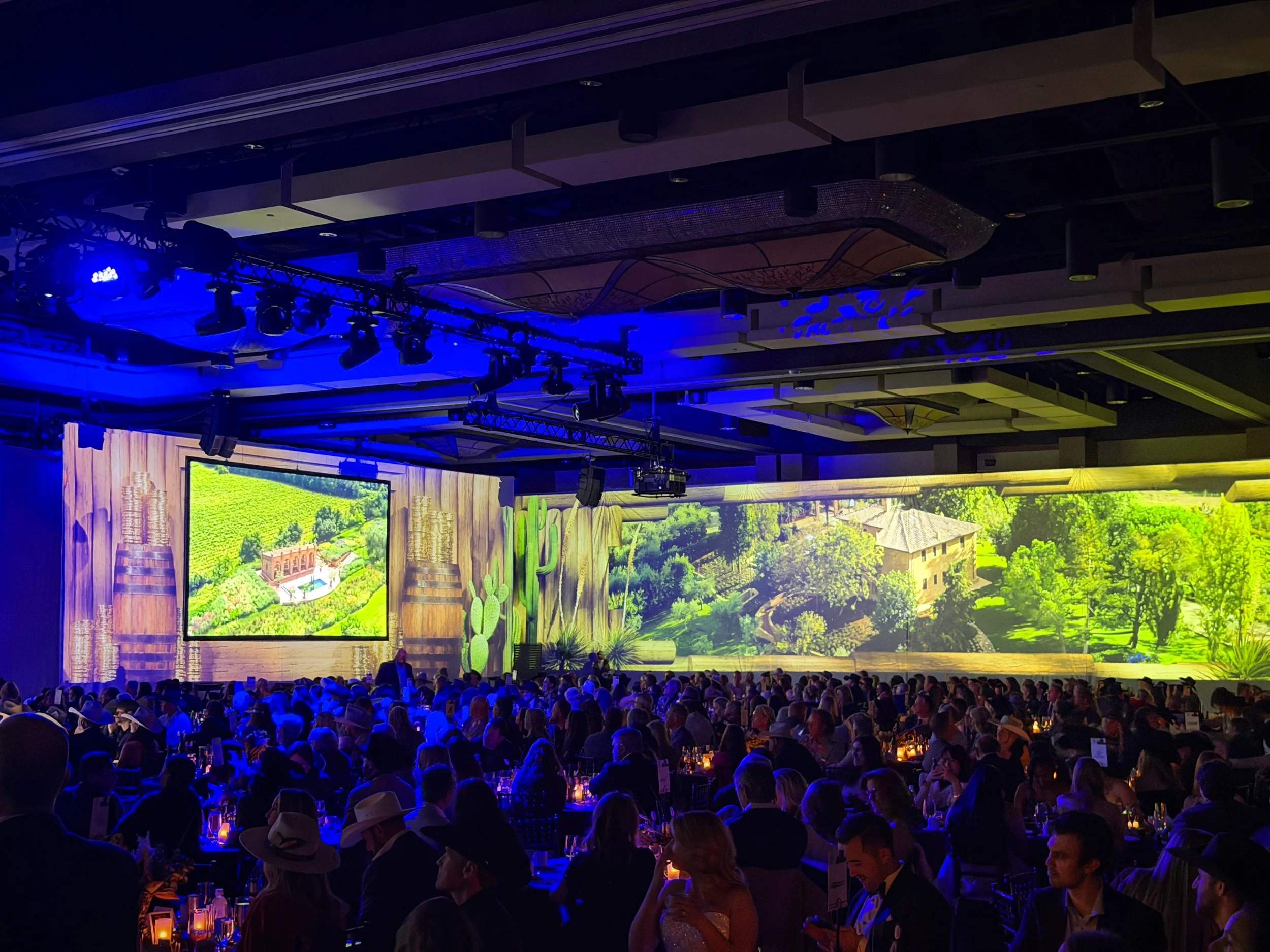 Event lighting design and wide screen projection at a corporate gala, vineyard landscape spanning the ballroom