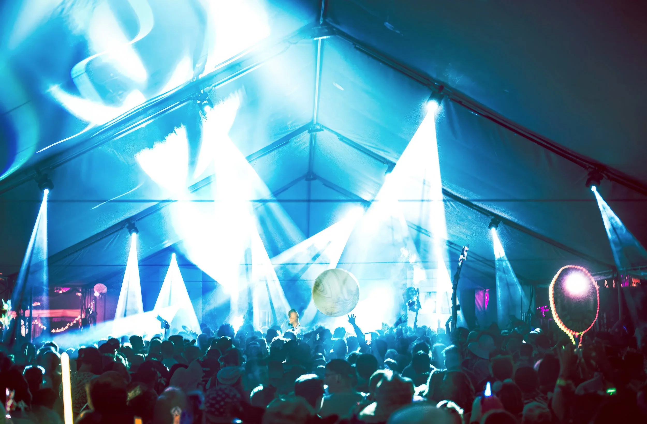Lighting design inside an event tent, beams crossing over the crowd and a mirror ball above the stage