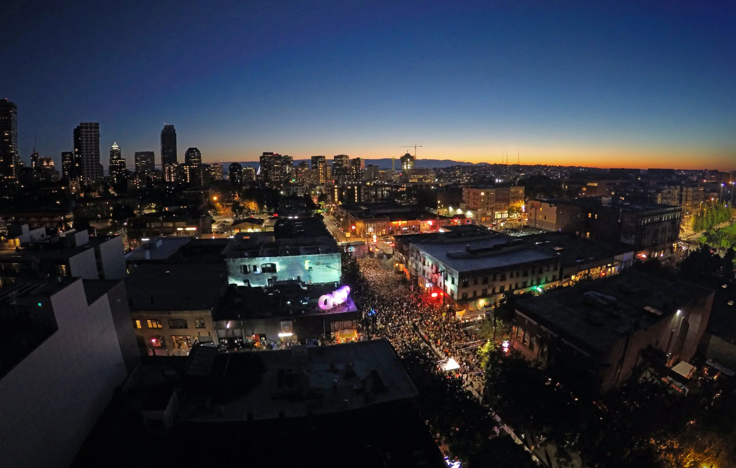 Capitol Hill Block Party projection mapping in Seattle, aerial dusk view over the skyline and packed crowd