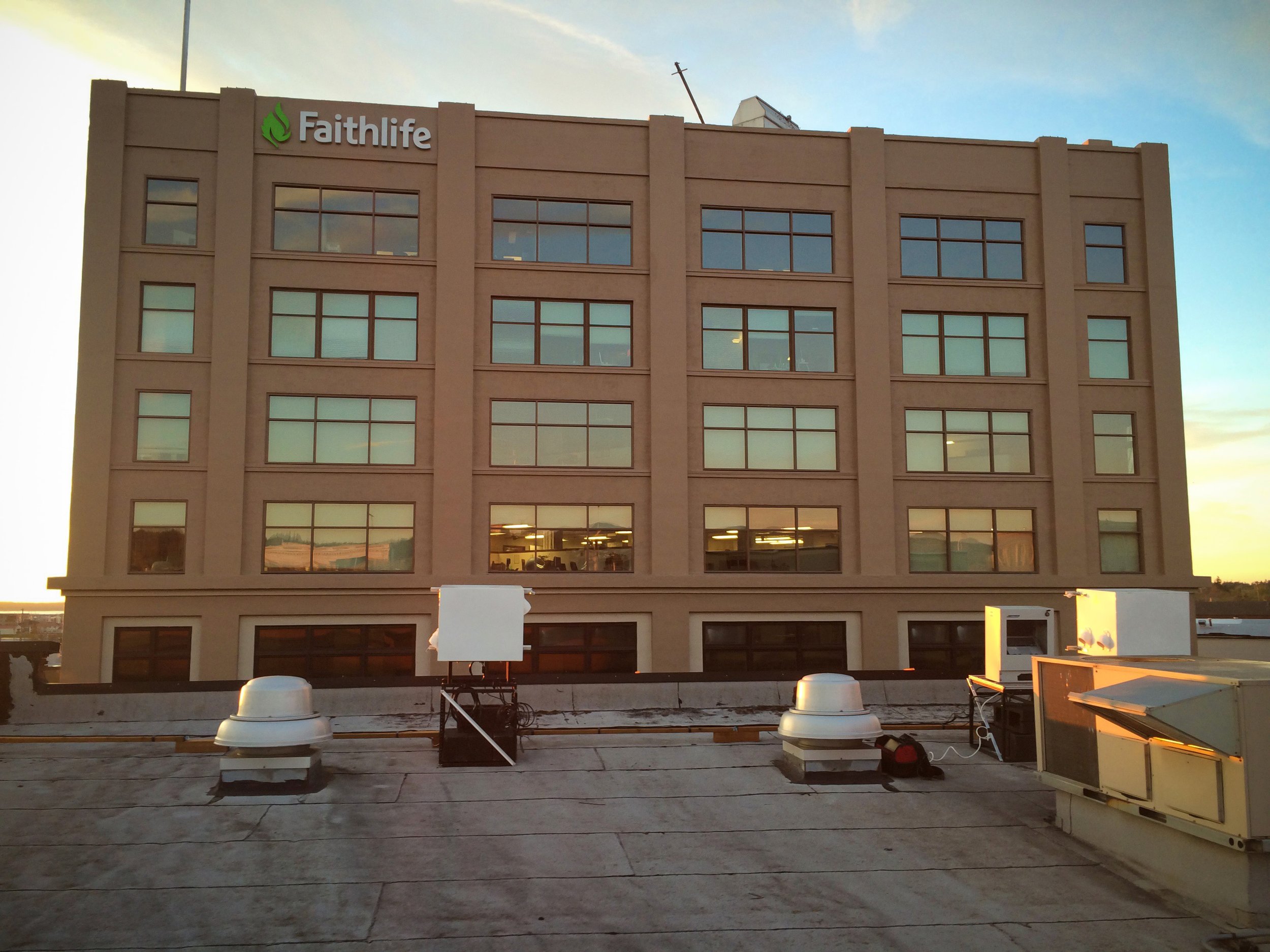 Faithlife projection mapping system in Bellingham, rooftop projector enclosures facing the building at golden hour.