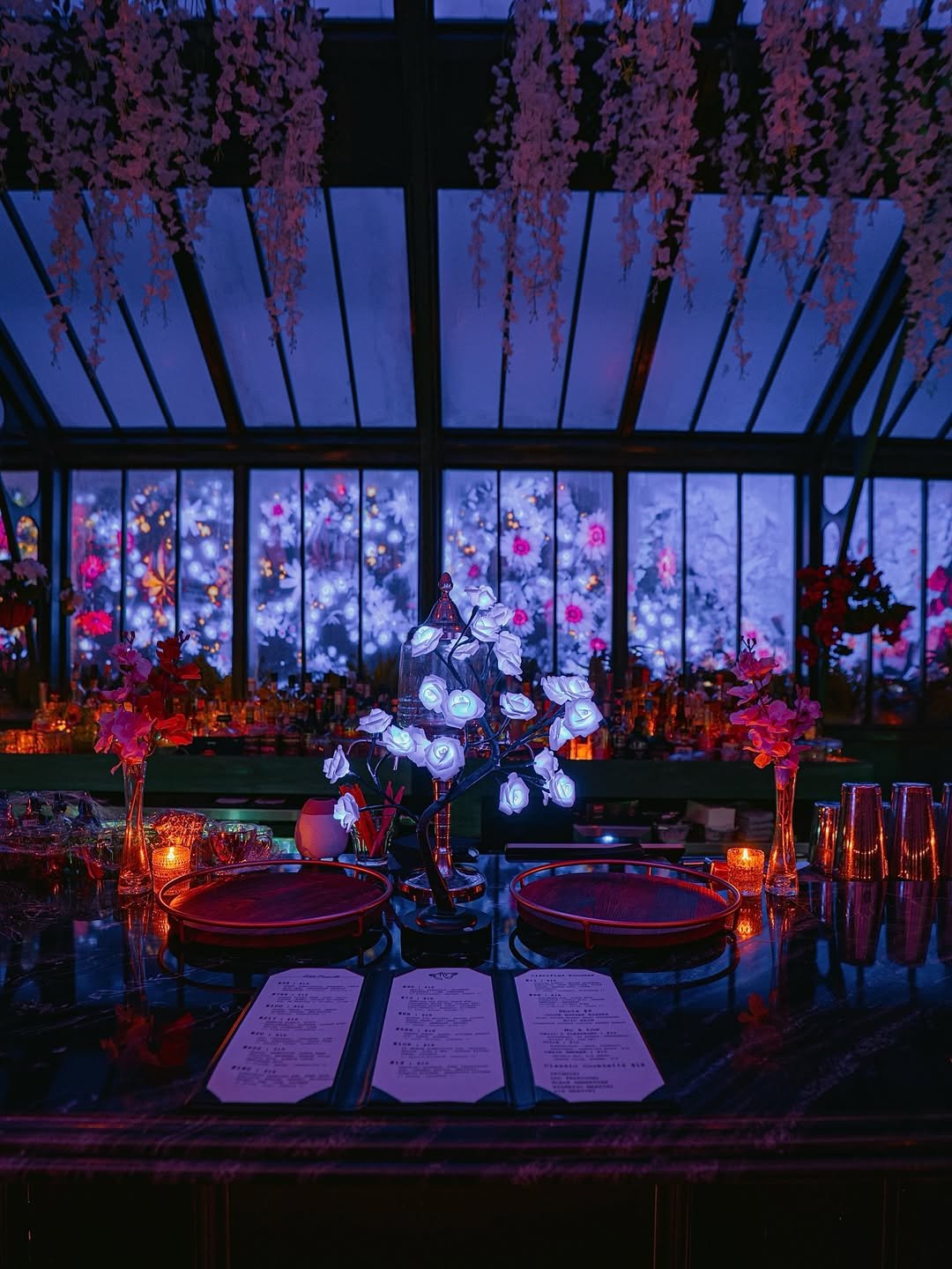 Spring custom visuals glowing through the windows behind the bar at Idle Hands Phoenix, lit roses on the marble bar top