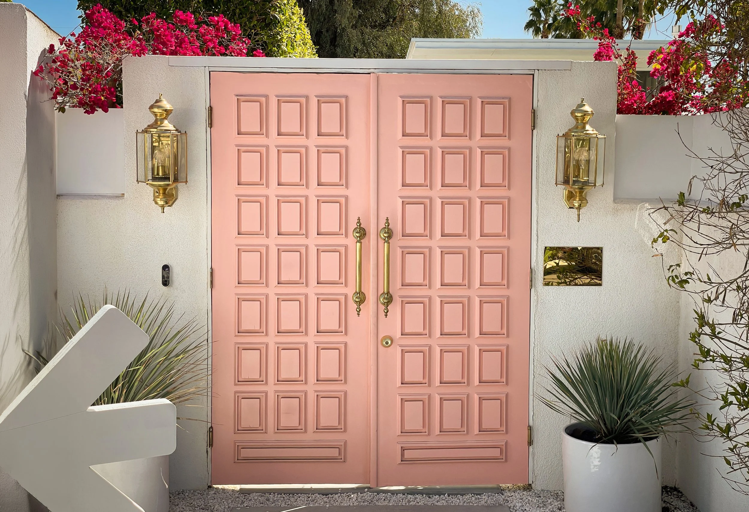 Galleri immersive dinner venue entrance at Knife House Palm Springs, pink double doors framed by bougainvillea