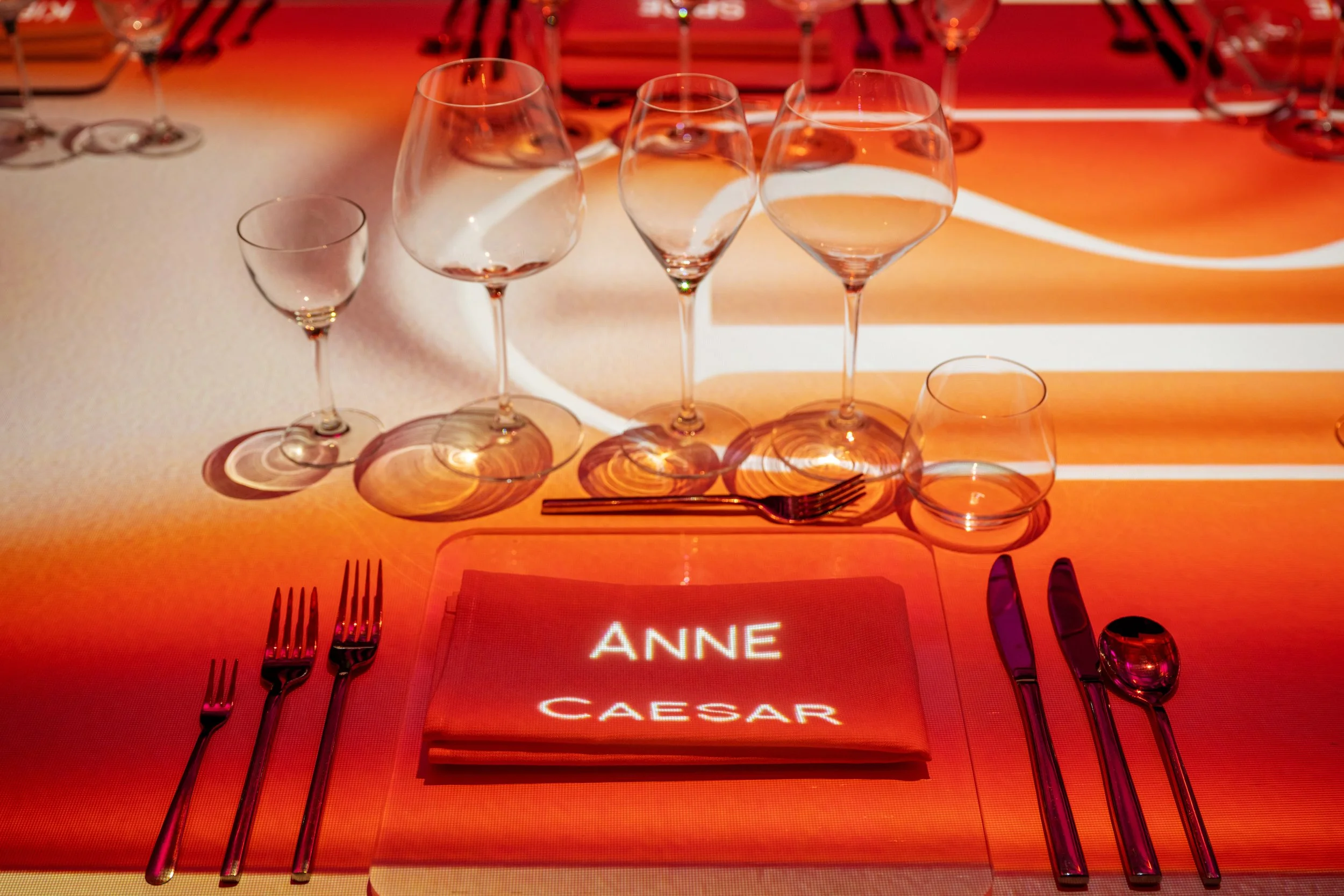 The Radiant Table immersive dining, guest name projected on a napkin at the amber mapped place setting