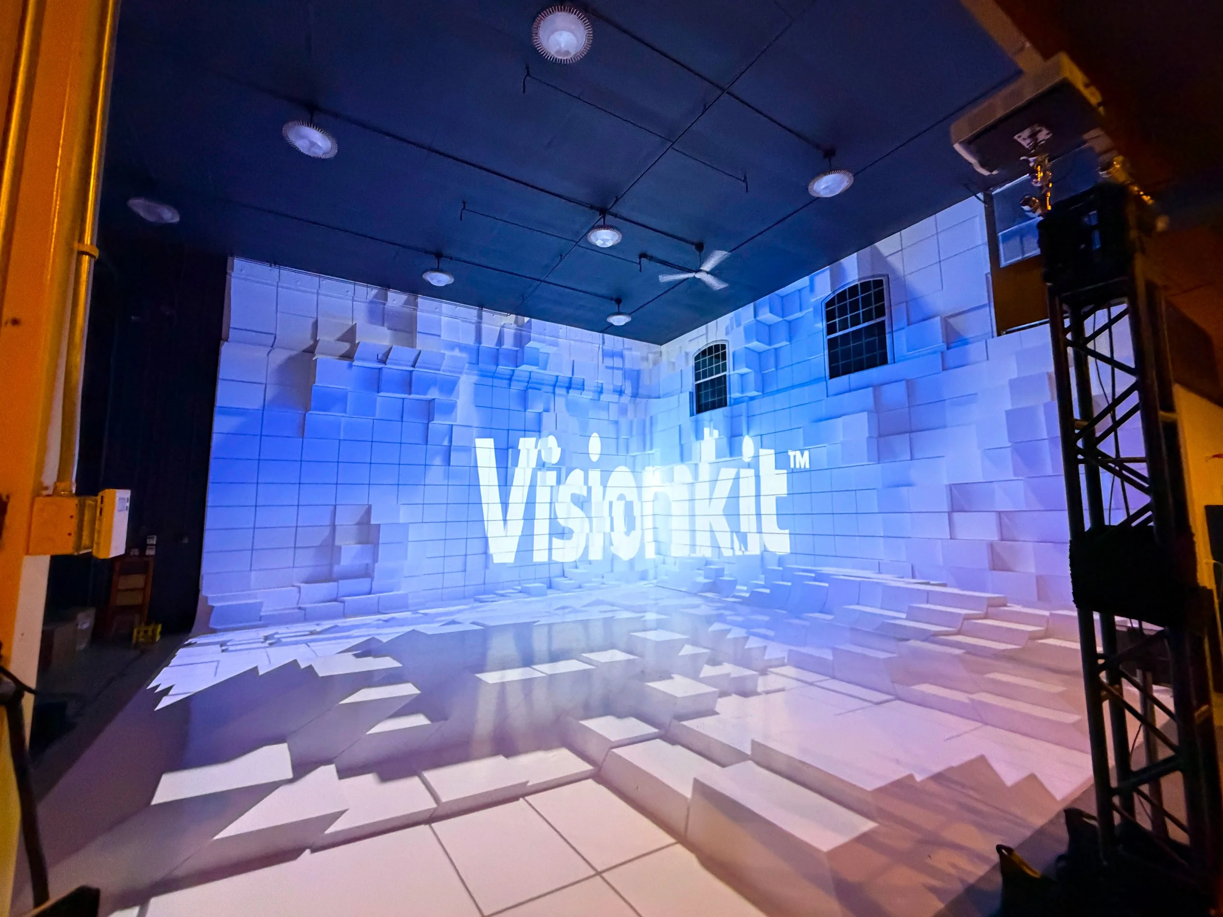 Projection mapping cyclorama wall at the Visionkit Studio open house in Garden City, Idaho, showing the logo in white relief