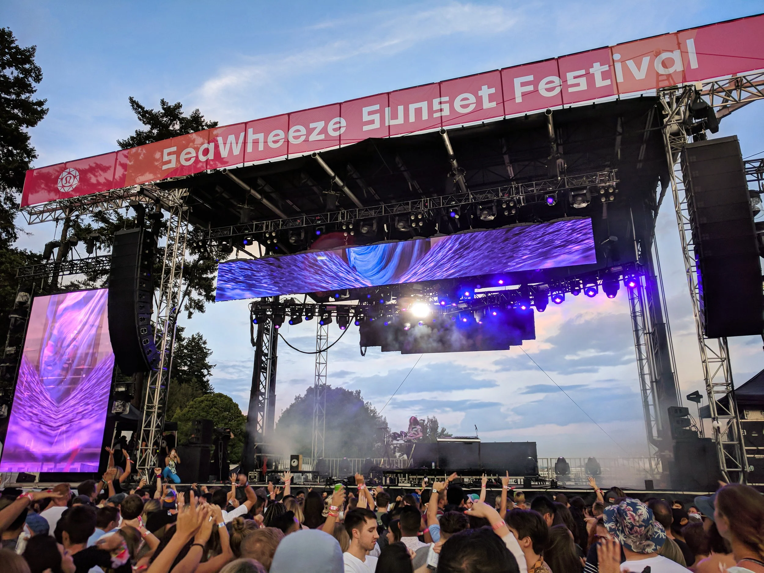 lululemon SeaWheeze festival main stage, crowd with hands raised under purple LED walls at dusk