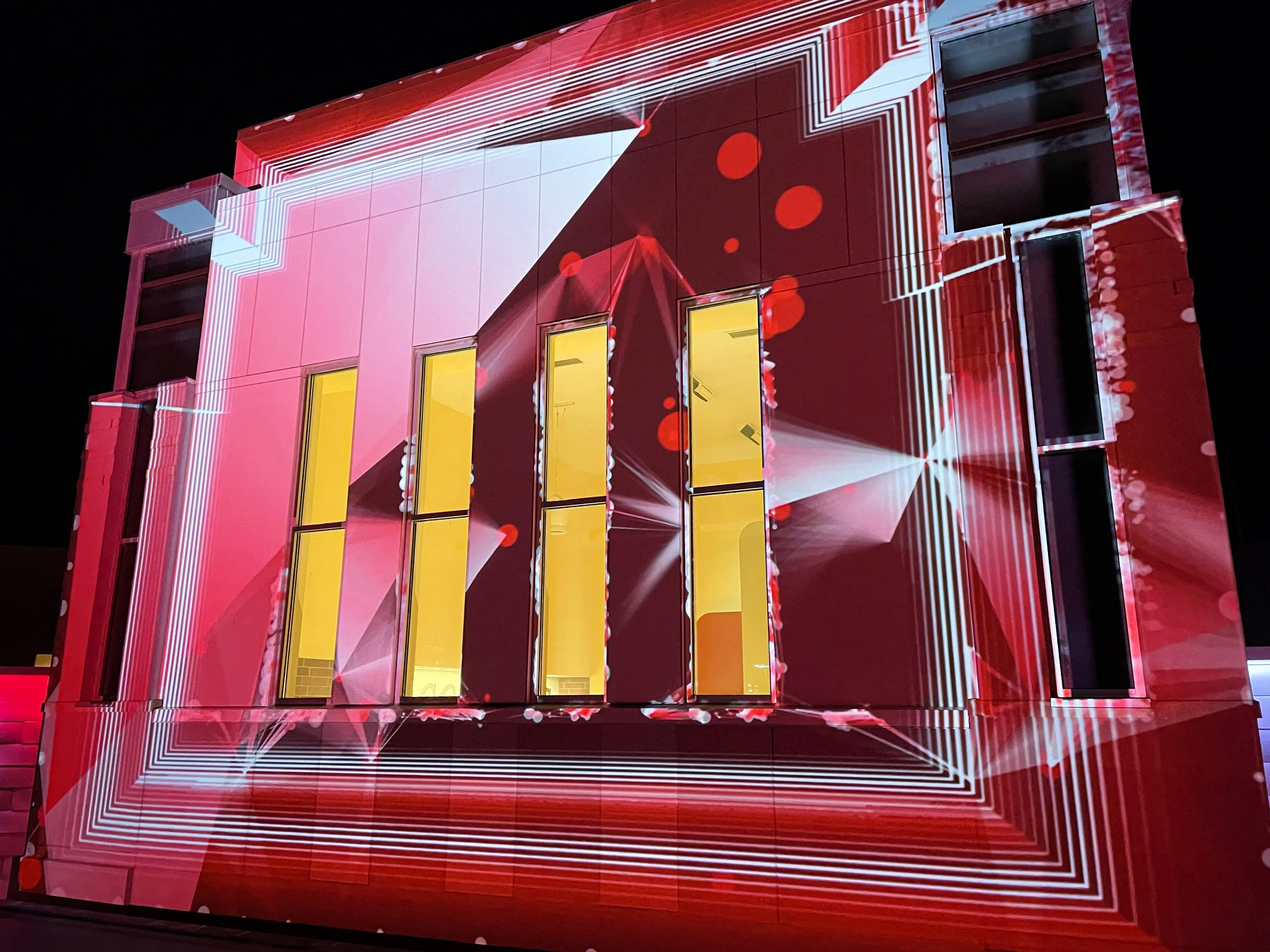 Running Aces Casino projection mapping, red geometric content mapped across the lit entrance tower.