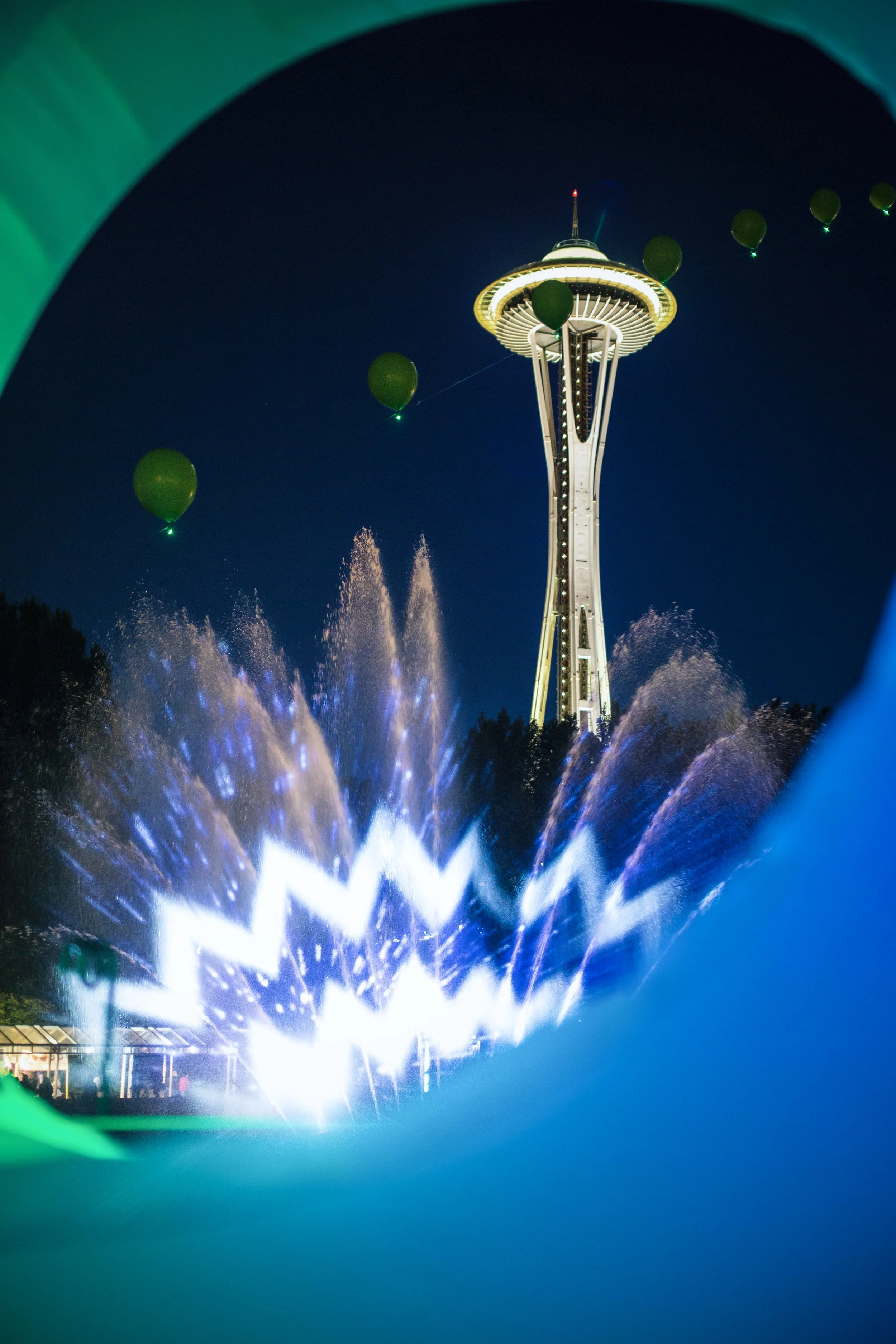 Bumbershoot International Fountain projection mapping, Space Needle over lit water and green balloons at Seattle Center