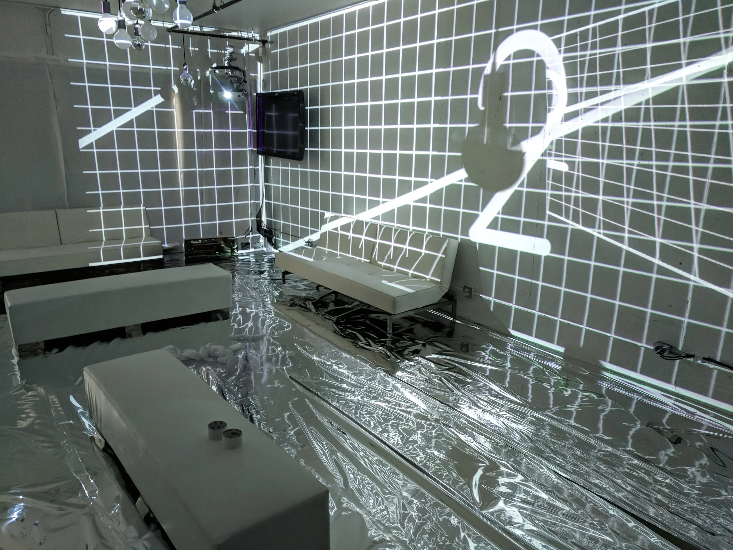 Fremont Foundry immersive room, white grid mapping with a headphone motif over lounge seating and Mylar floor