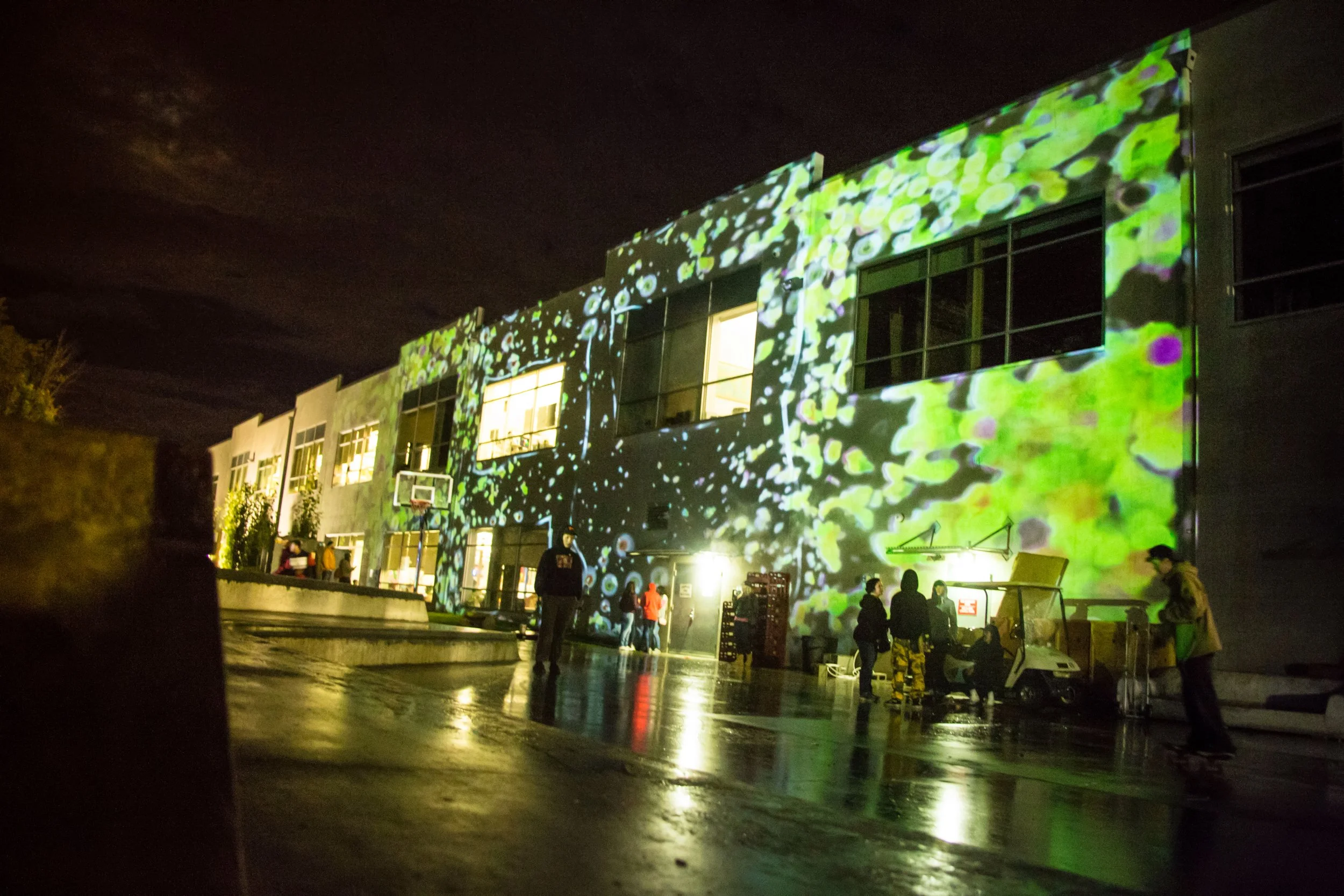 Green projection mapping content splashes across the Zumiez headquarters facade during the Best Foot Forward finals in Lynnwood, Washington
