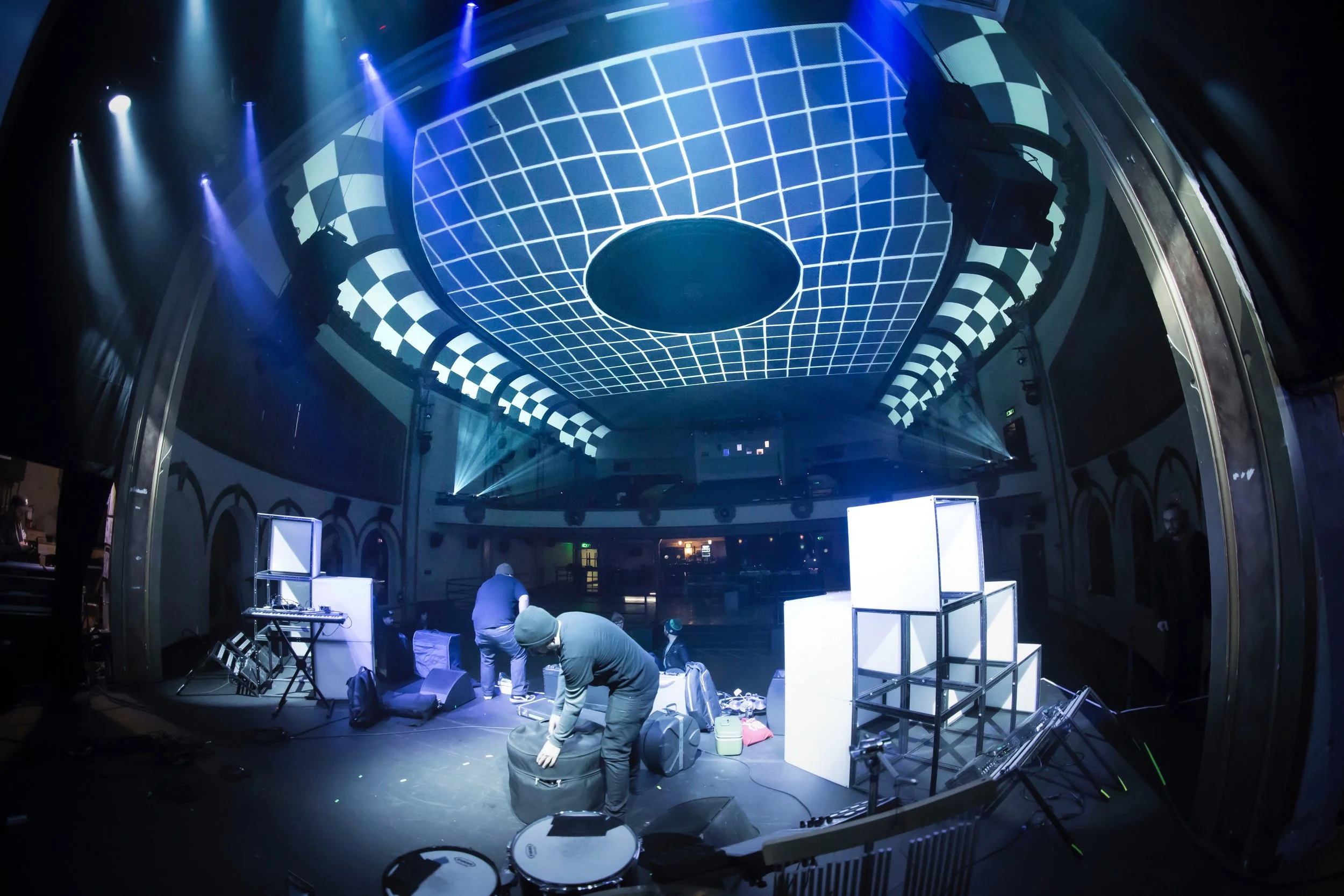 Projection mapping setup at the Neptune Theatre in Seattle, blue grid test pattern on the ceiling, crew assembling cubes