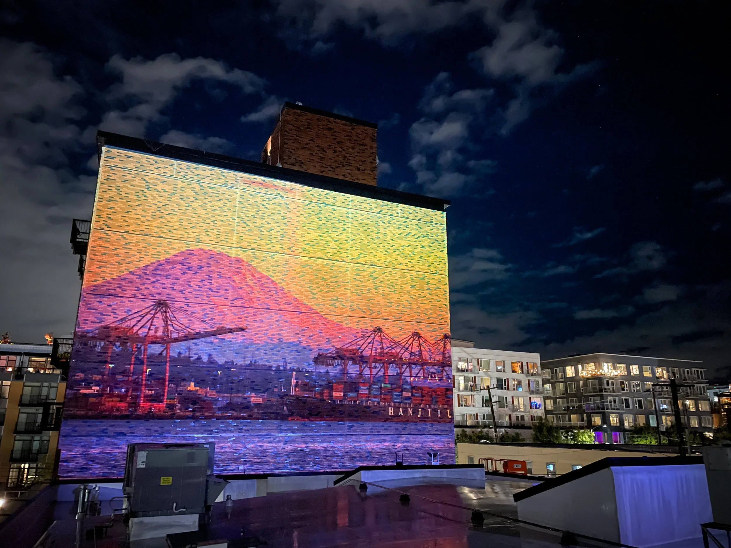 Woodworth Apartments projection mapping, Capitol Hill Seattle, Mount Rainier and port cranes on the brick wall.