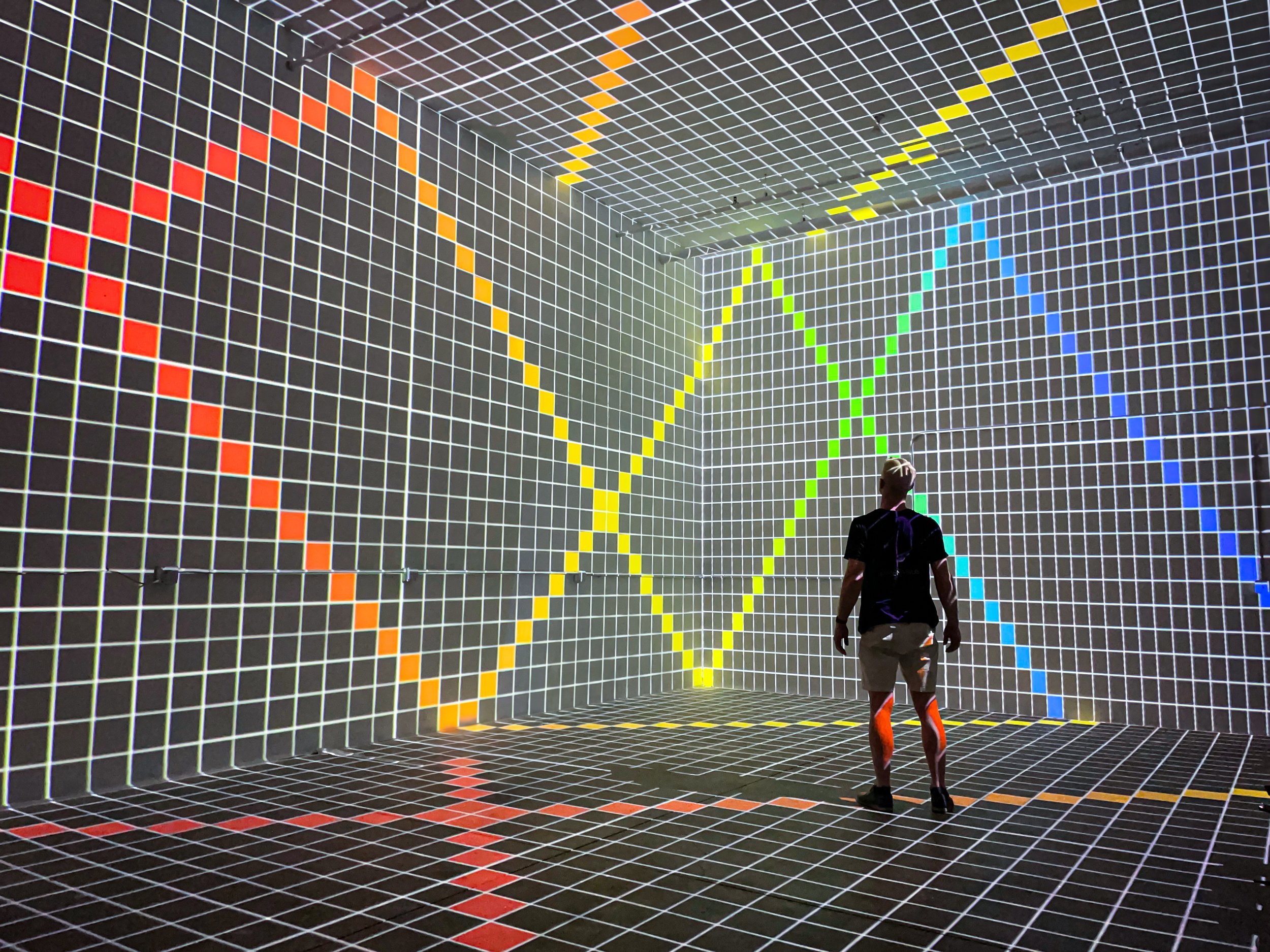 In studio immersive projection room by NOVA Light Labs, guest inside a calibration grid mapped wall to floor.
