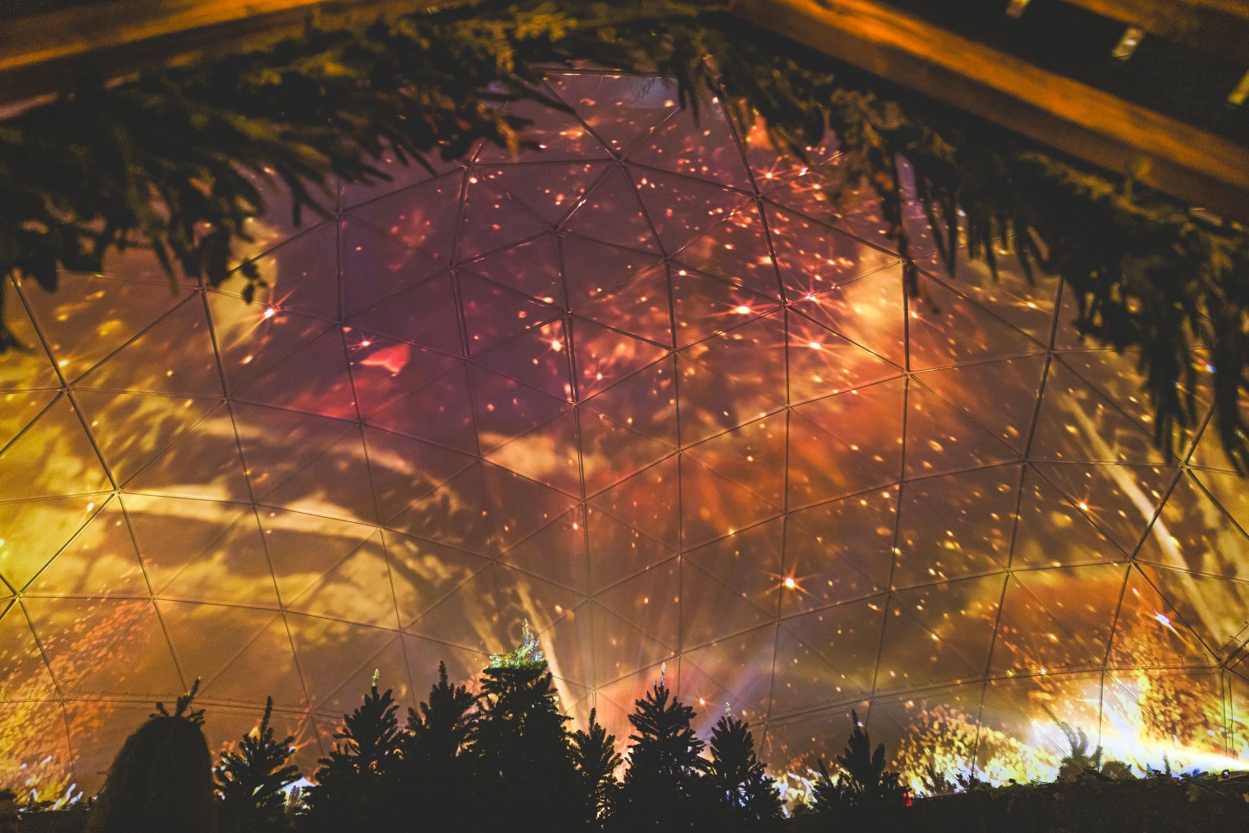 Ember Lounge dome projection mapping at Desert Ridge Marketplace, amber firelight and sparks over silhouetted pines
