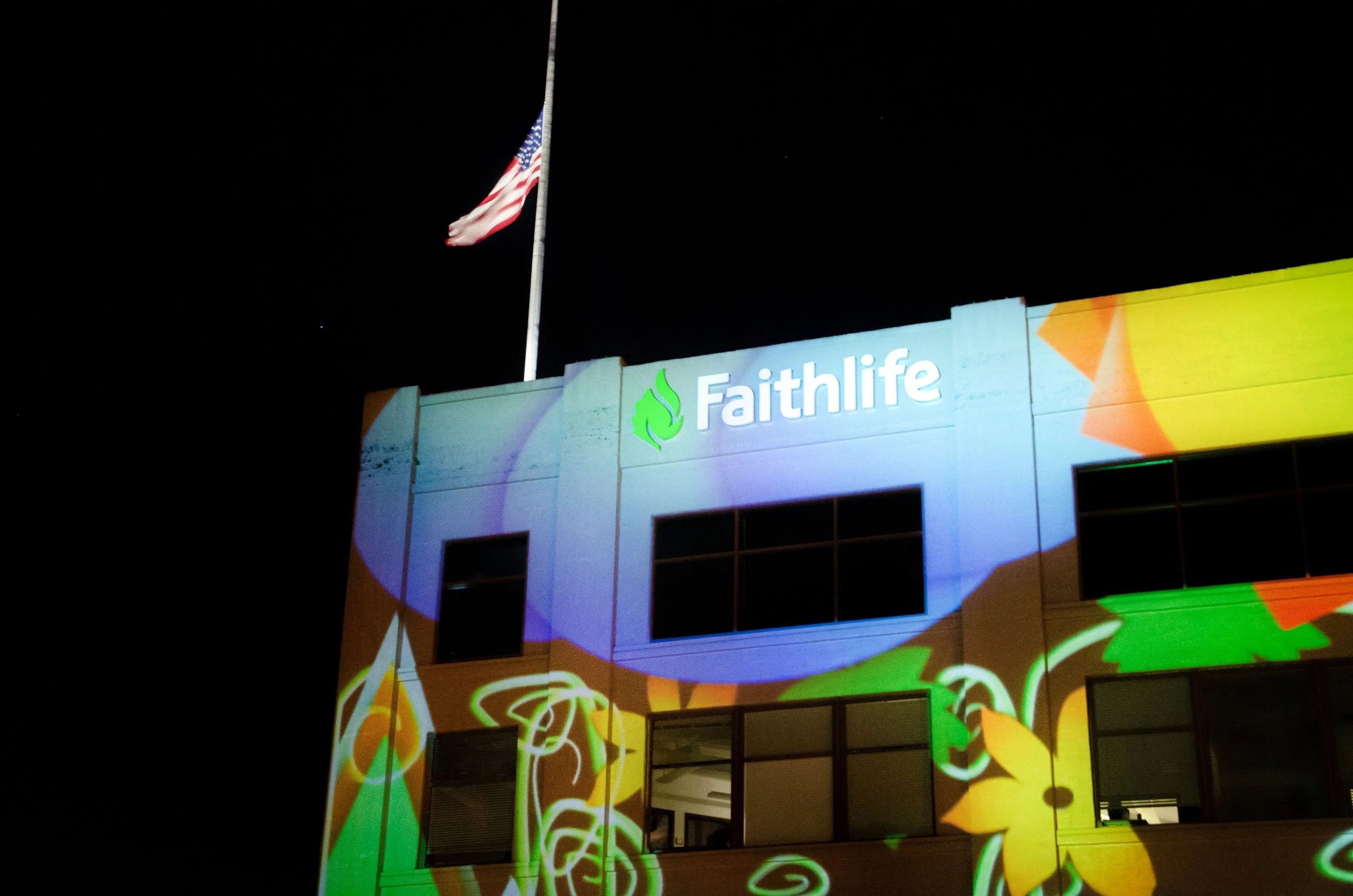 Faithlife projection mapping in downtown Bellingham, floral custom visuals across the facade below the illuminated logo.