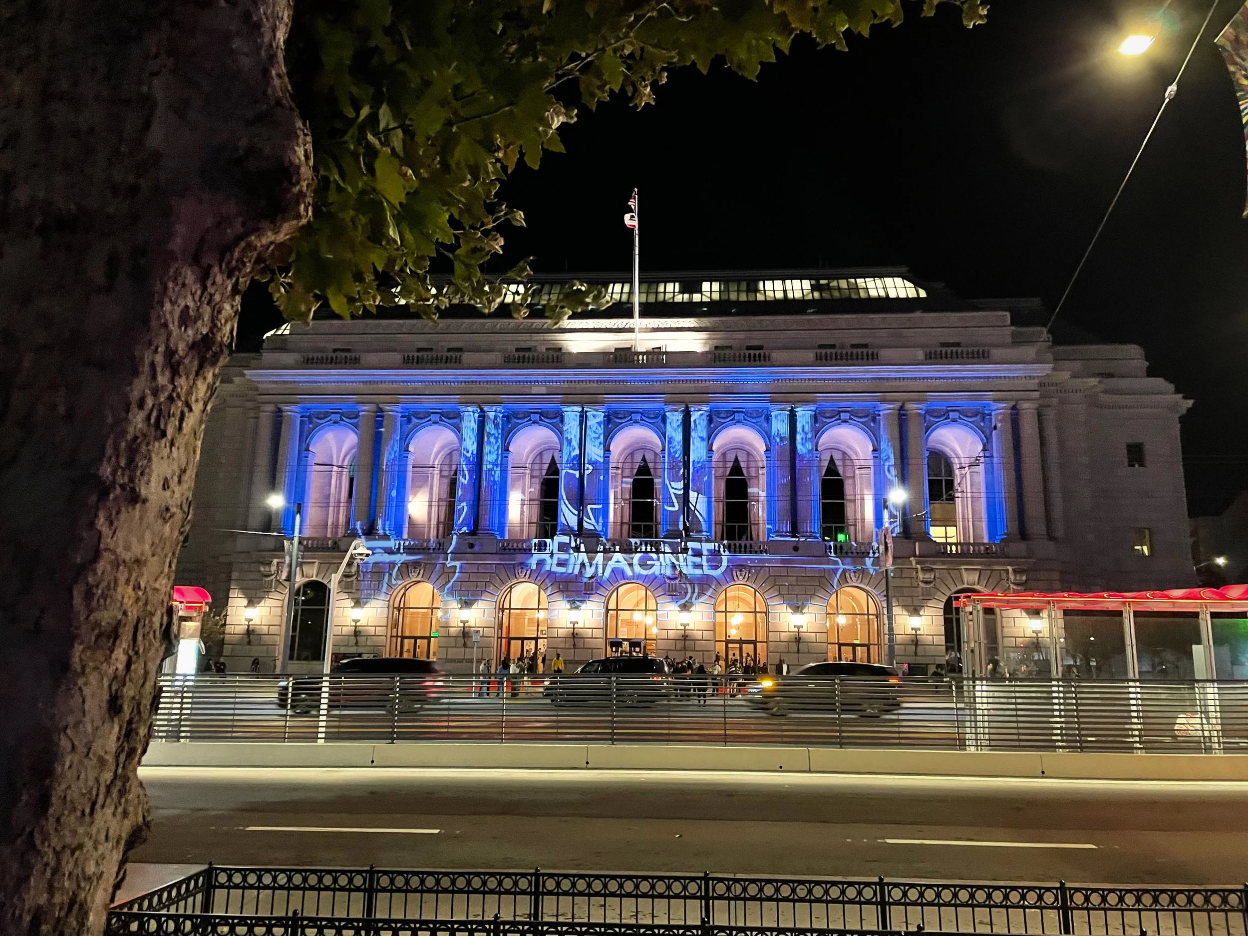 Herbst Theatre projection mapping in San Francisco, full neoclassical facade at night with REIMAGINED across it