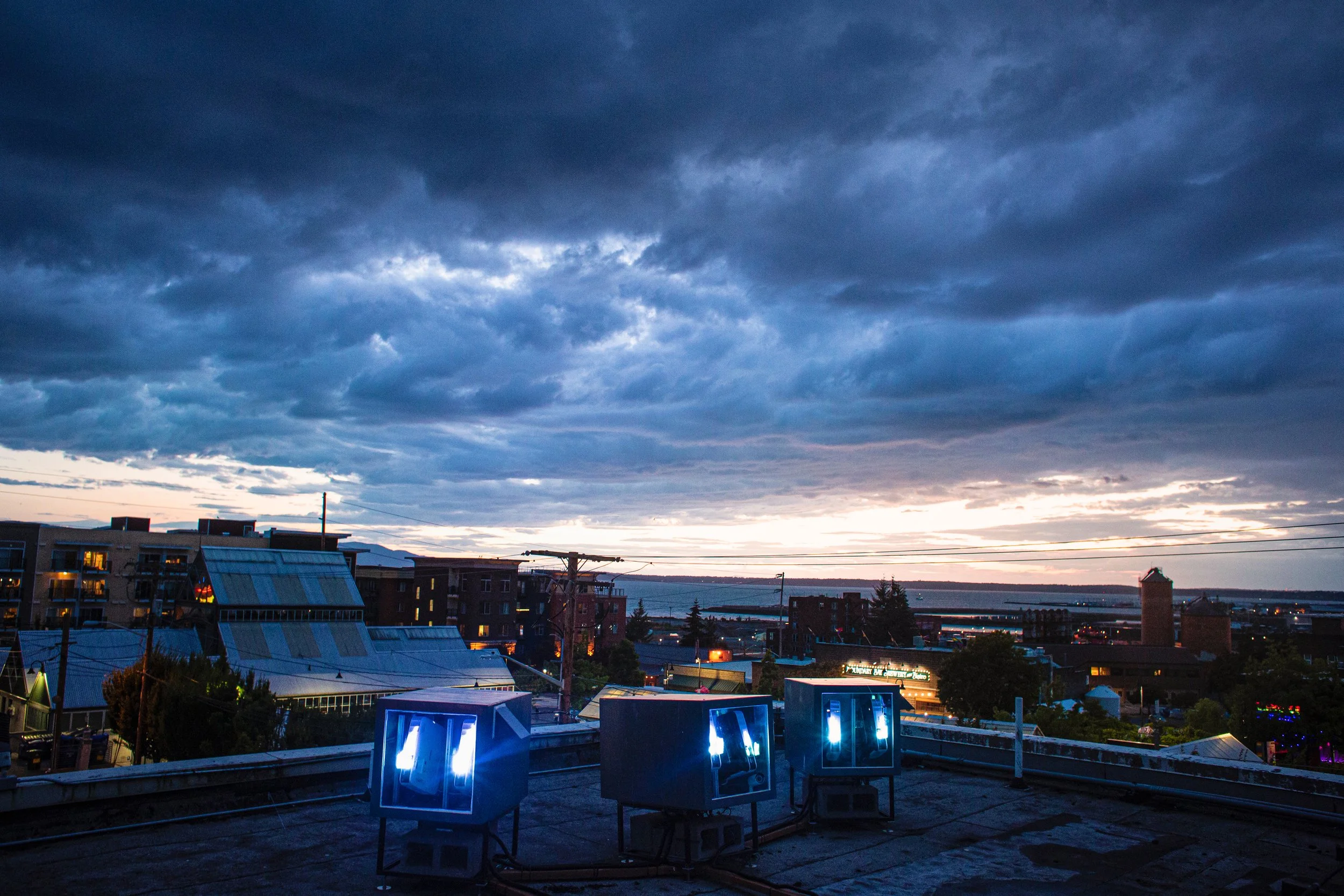 The Herald projection mapping system in Bellingham, 3 weatherproof projector enclosures on the rooftop at dusk.