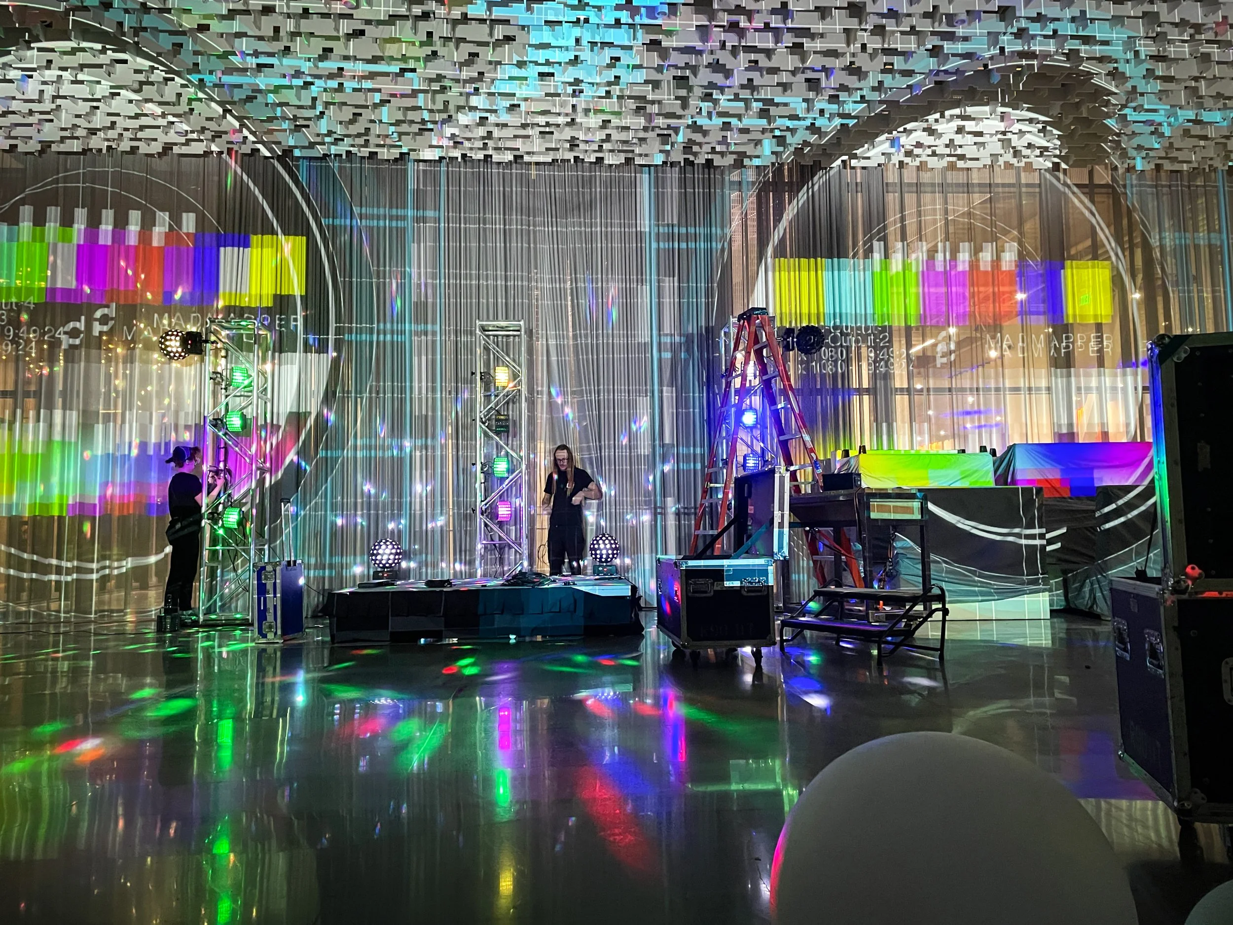 Load in for a live event projection mapping build, test patterns on the walls and crew staging gear on the floor