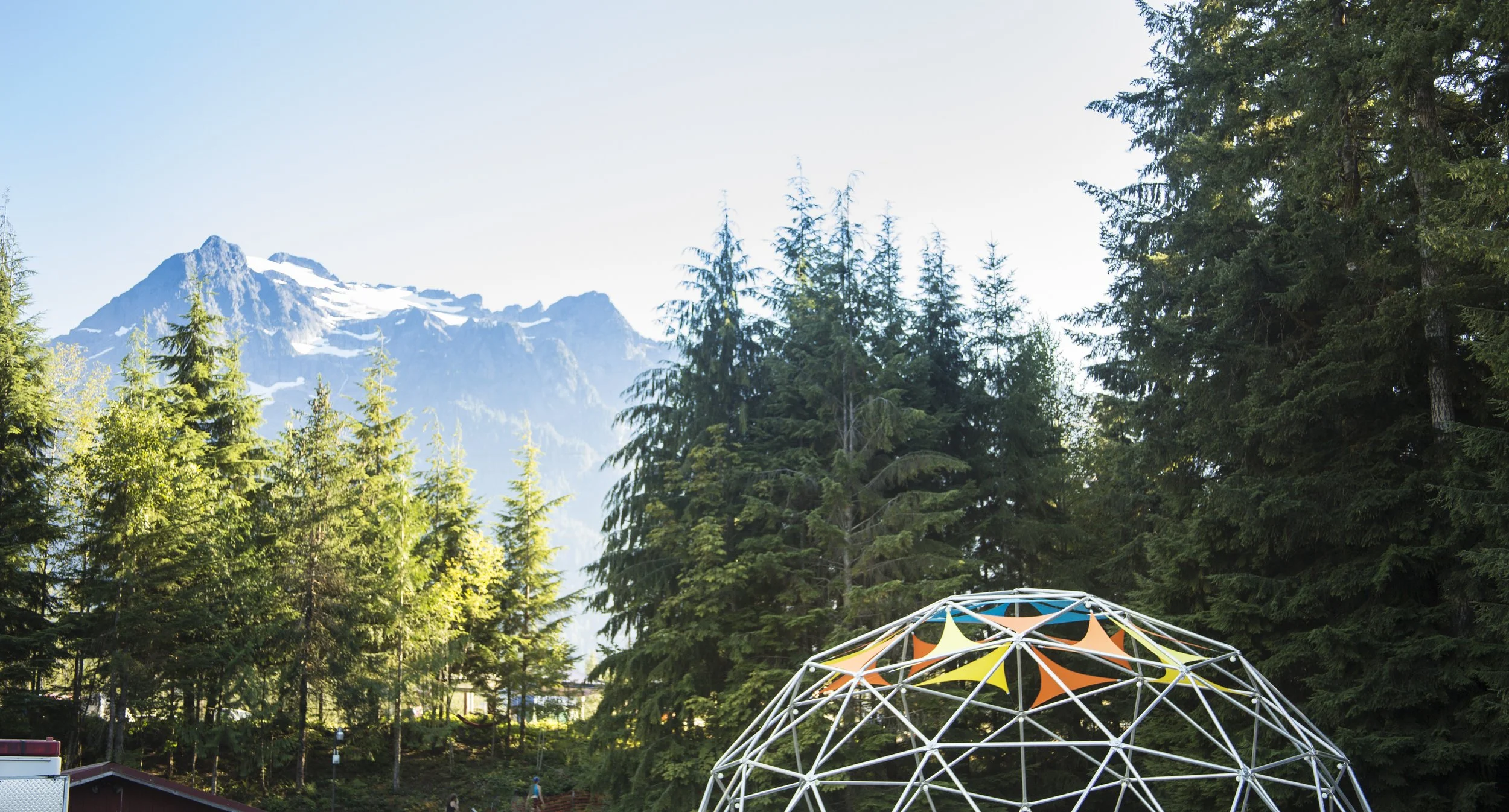 Geodesic dome at Summer Meltdown in Darrington, Washington, colored sail panels under Whitehorse Mountain at sunset.