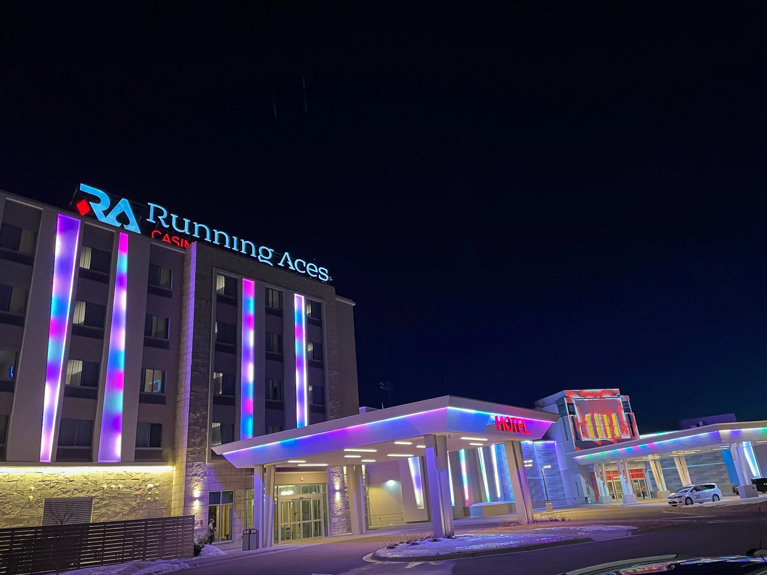 Running Aces Casino lighting design and projection mapping, night view of the lit hotel and entrance canopy.