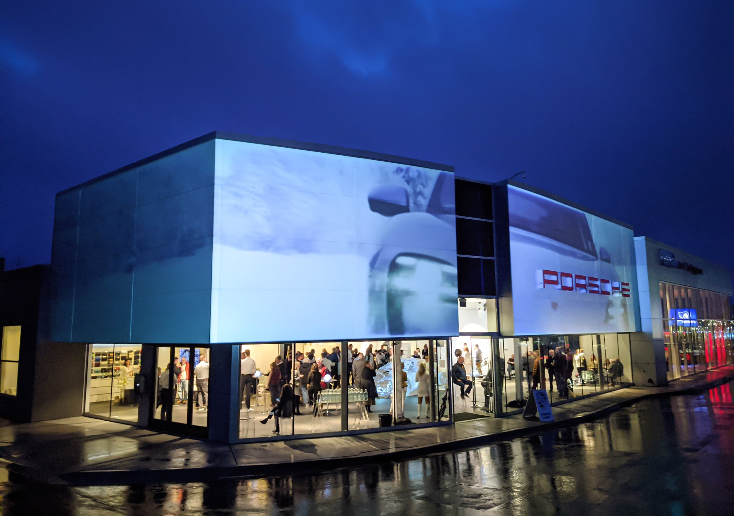 Porsche Taycan unveil projection mapping in Bellingham, Washington, dealership facade lit at dusk