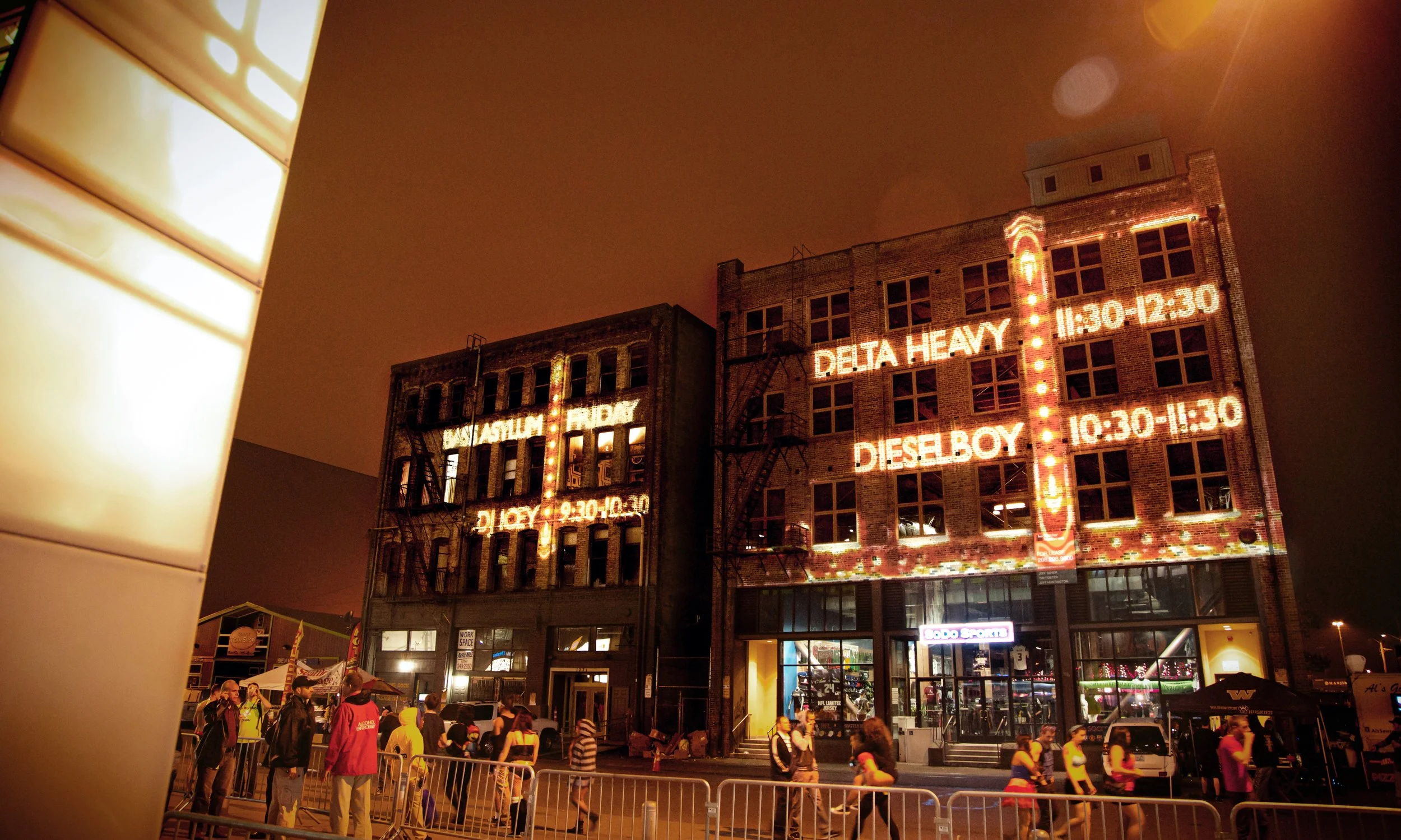 Freaknight Music Festival projection mapping in downtown Seattle, DJ lineup and set times across brick facades