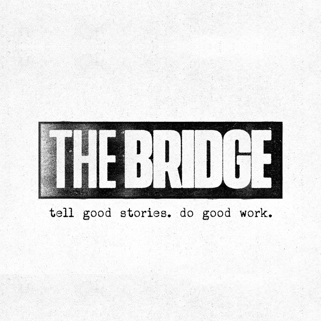 Logo for the organization 'The Bridge' with the slogan 'tell good stories. do good work.' in black and white.