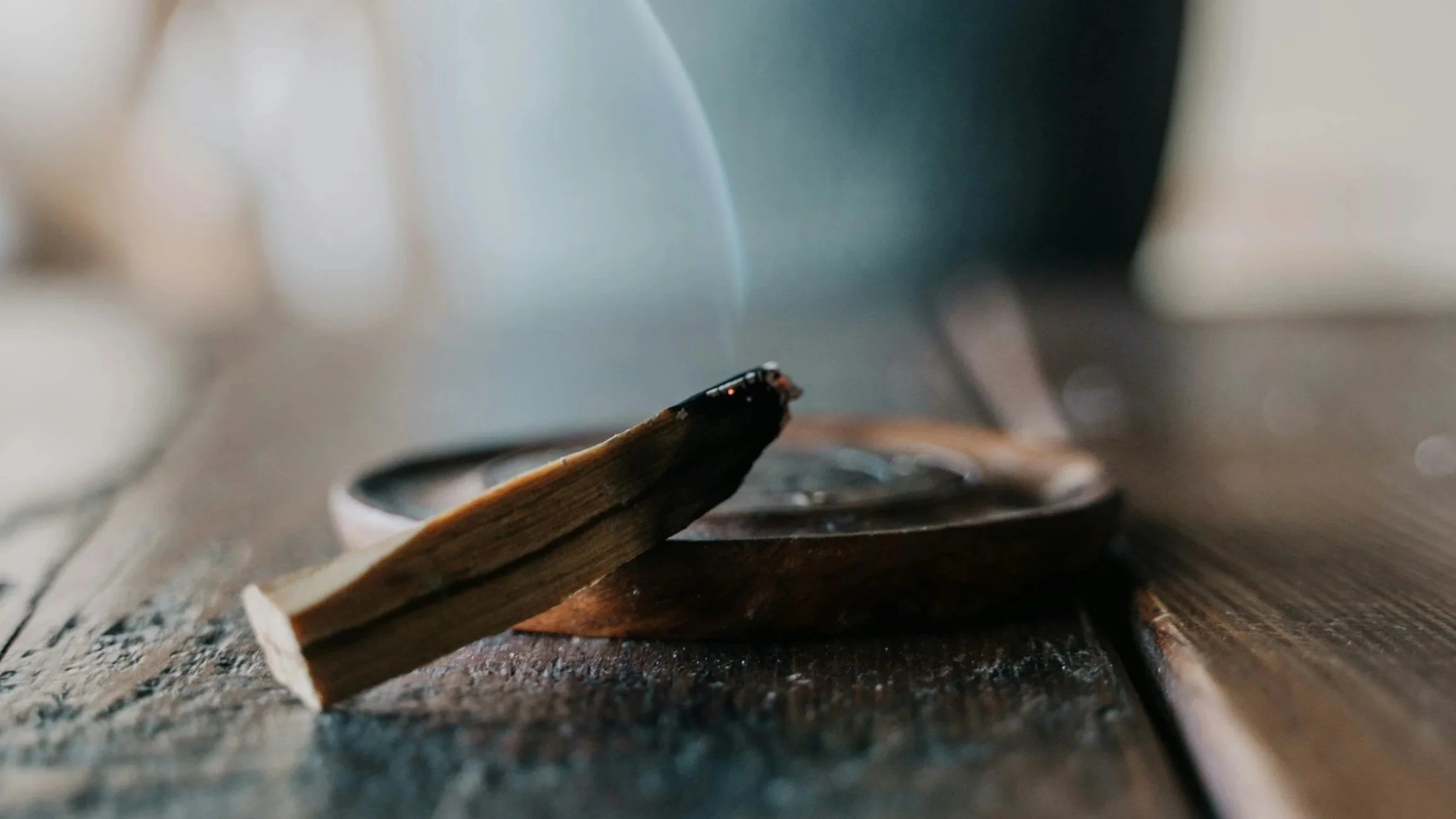 Close-up of a lit matchstick on a wooden surface with a blurred background.