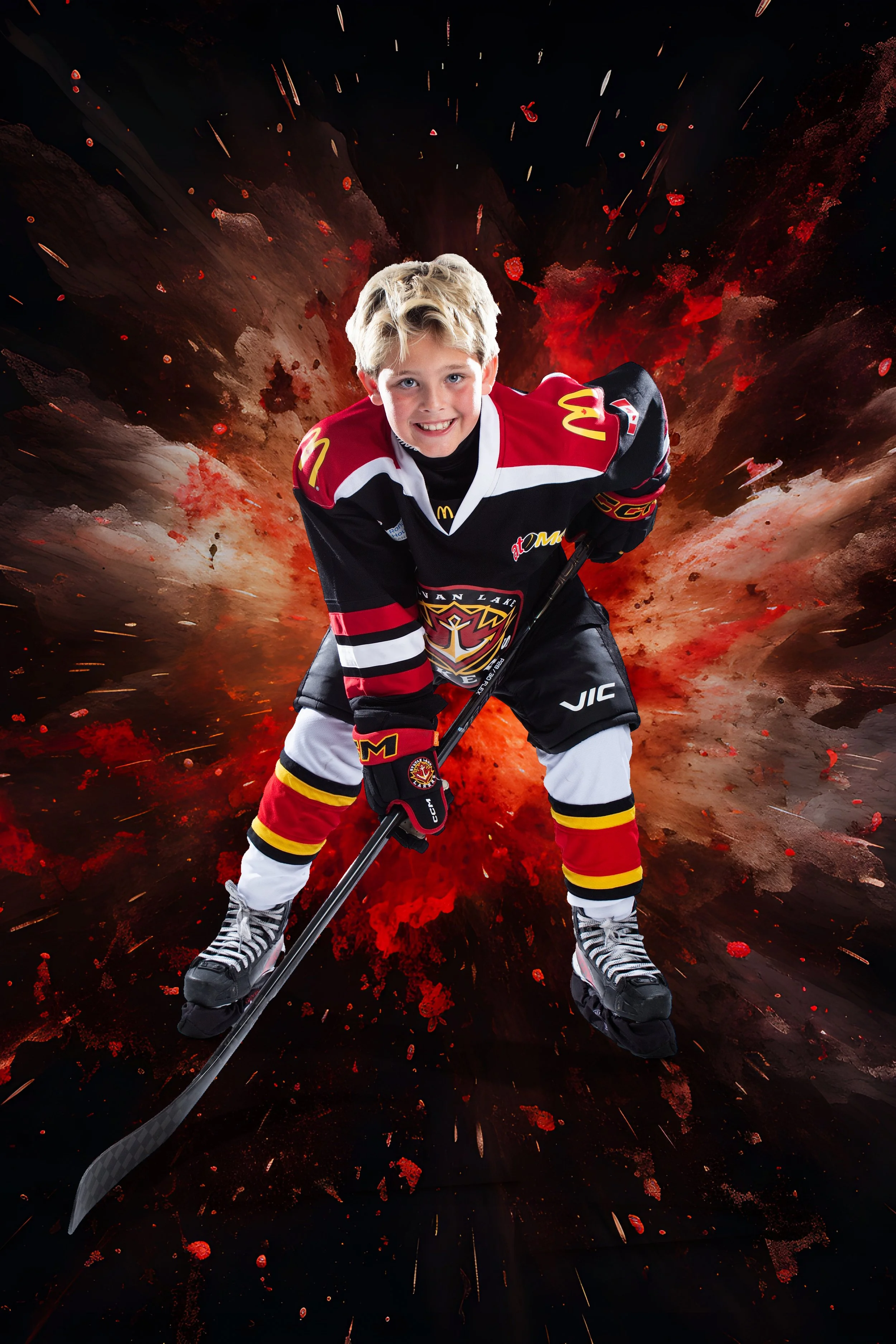 Young boy wearing a hockey uniform, smiling and posing with a hockey stick against a dramatic explosion background.