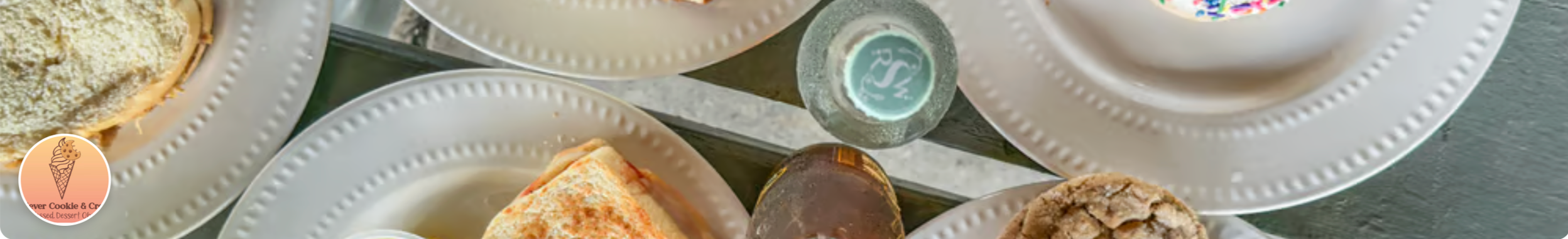 Dessert plates with various ice cream and cookie desserts, including ice cream cones and scoops, on a glass table.