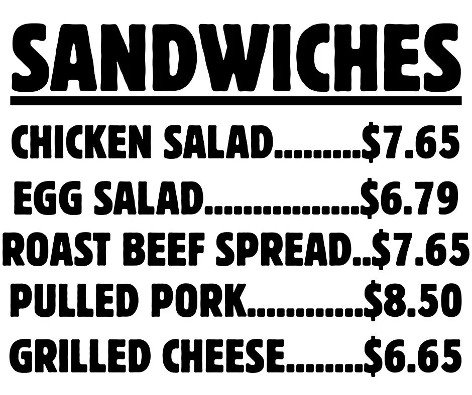Menu sign listing sandwich options with prices, including chicken salad, egg salad, roast beef spread, pulled pork, and grilled cheese.