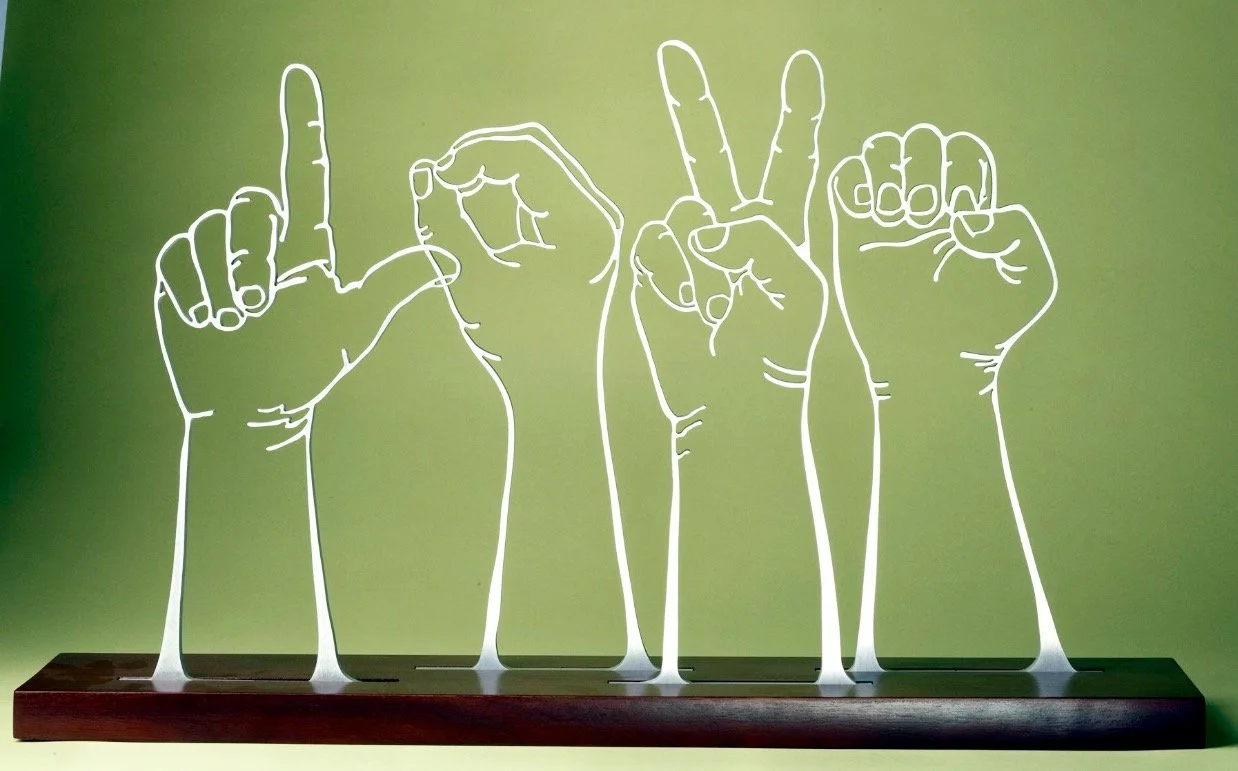 An art piece spelling Love in sign language. hands are carved from 1/2 inch aluminum and mounted on a  stained wooden base.