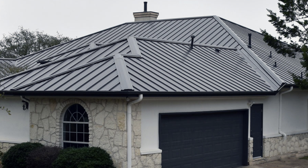 Residential house with stone and white siding walls, standing seam metal roof, arched window, and a black garage door.