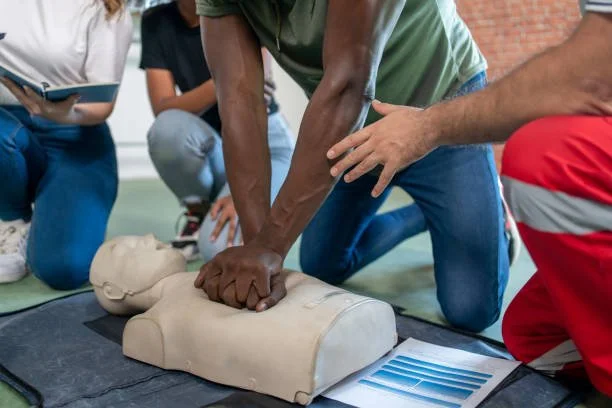 People practicing CPR on a training mannequin during a CPR class.