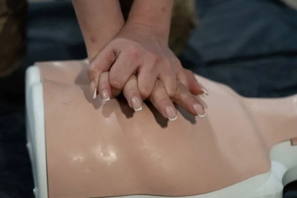 A person practicing CPR on a training mannequin, demonstrating chest compressions.