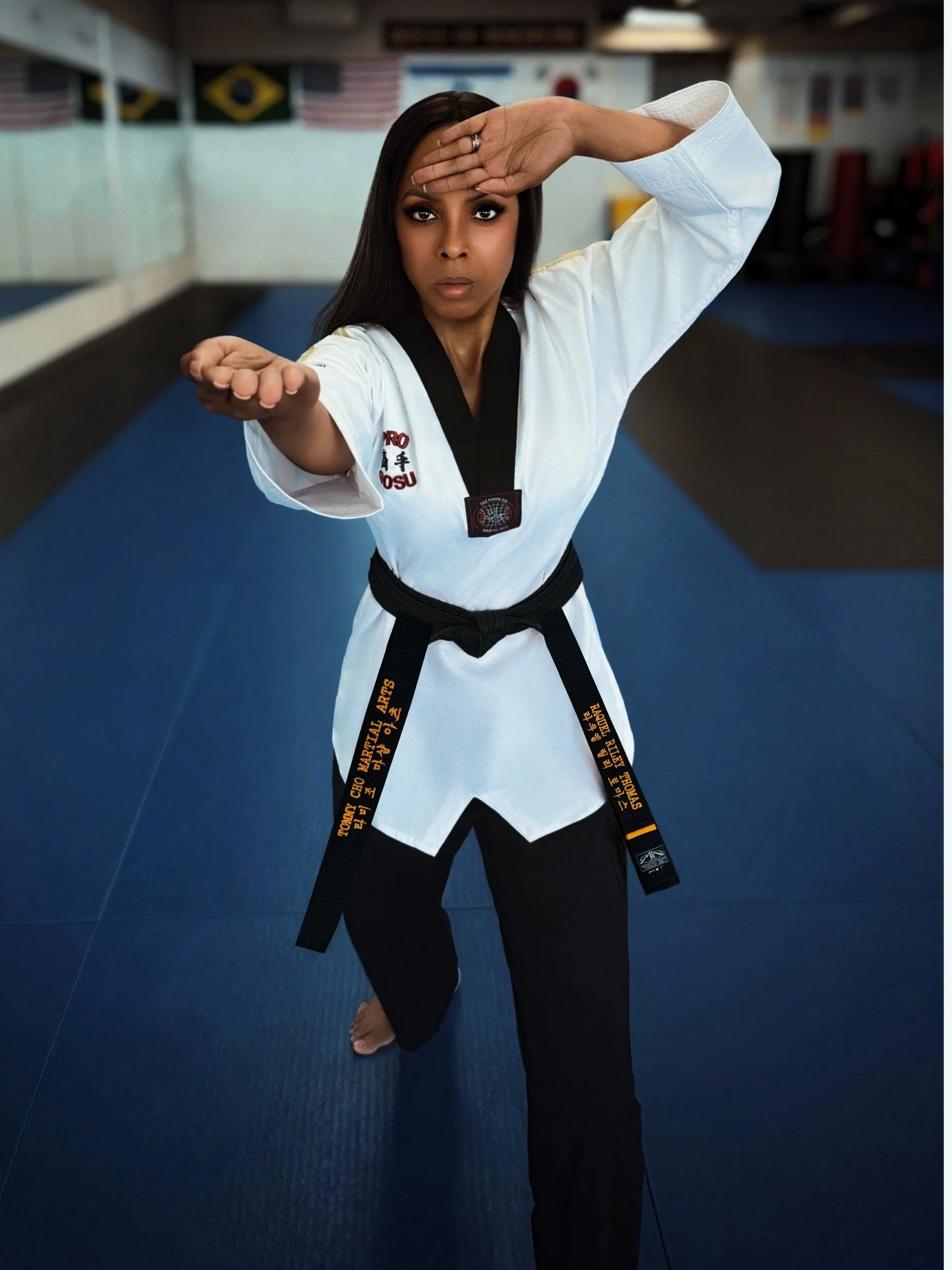 A woman in a martial arts uniform performing a front kick in a martial arts dojo.