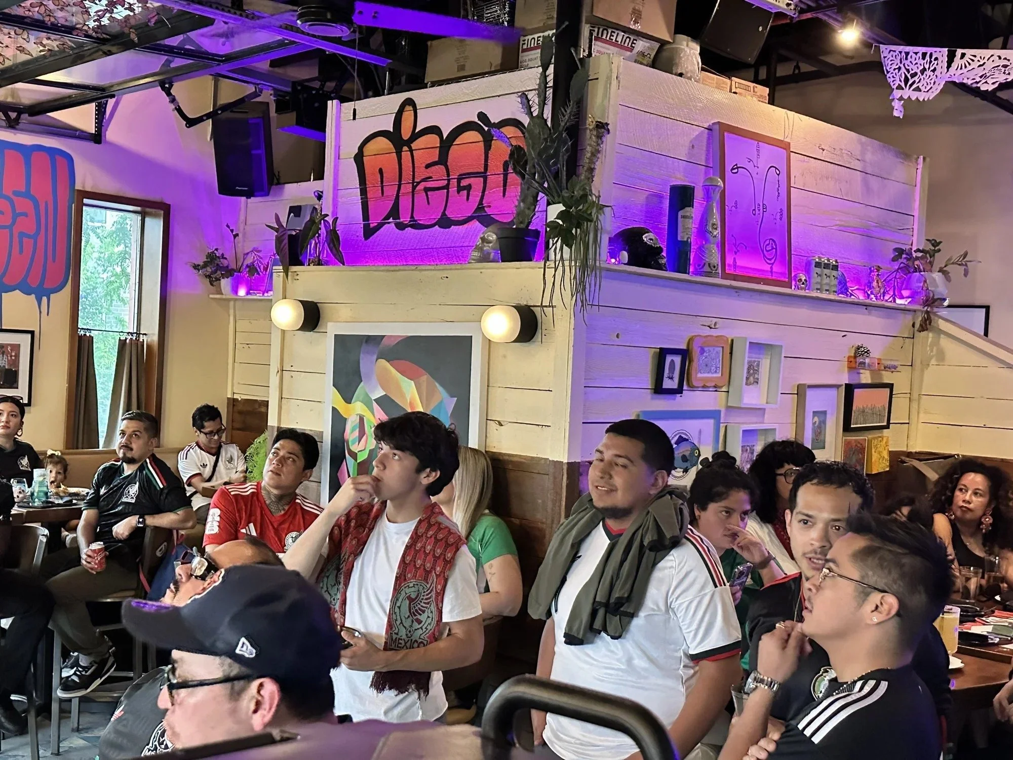 Fans watching a game under the Diego sign at the bar in West Town