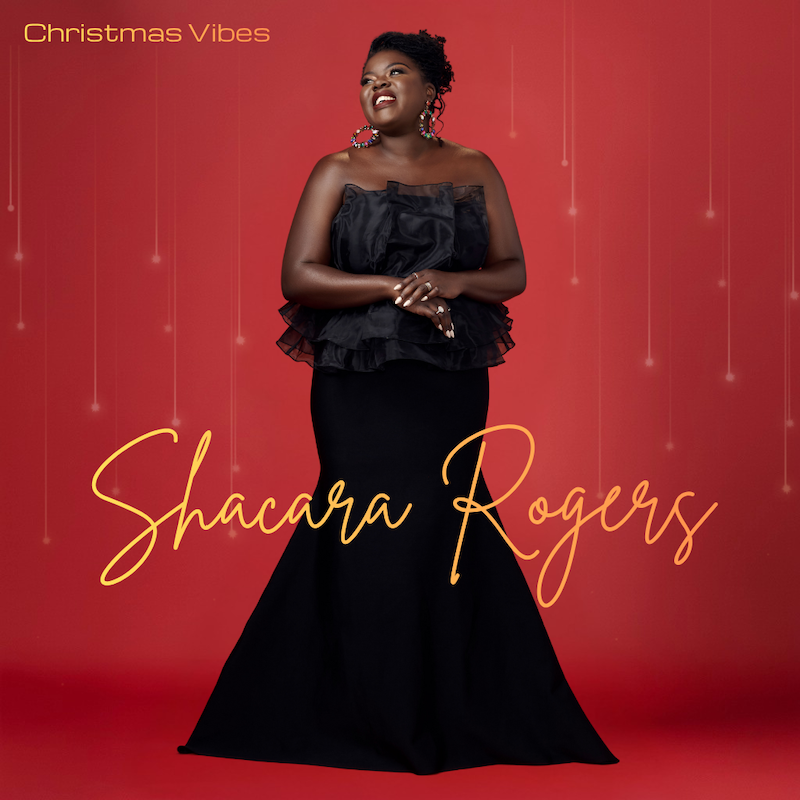 A woman in a black dress standing against a red background with hanging lights, smiling and looking up, with the text 'Christmas Vibes' and 'Shacara Rogers' in elegant script.