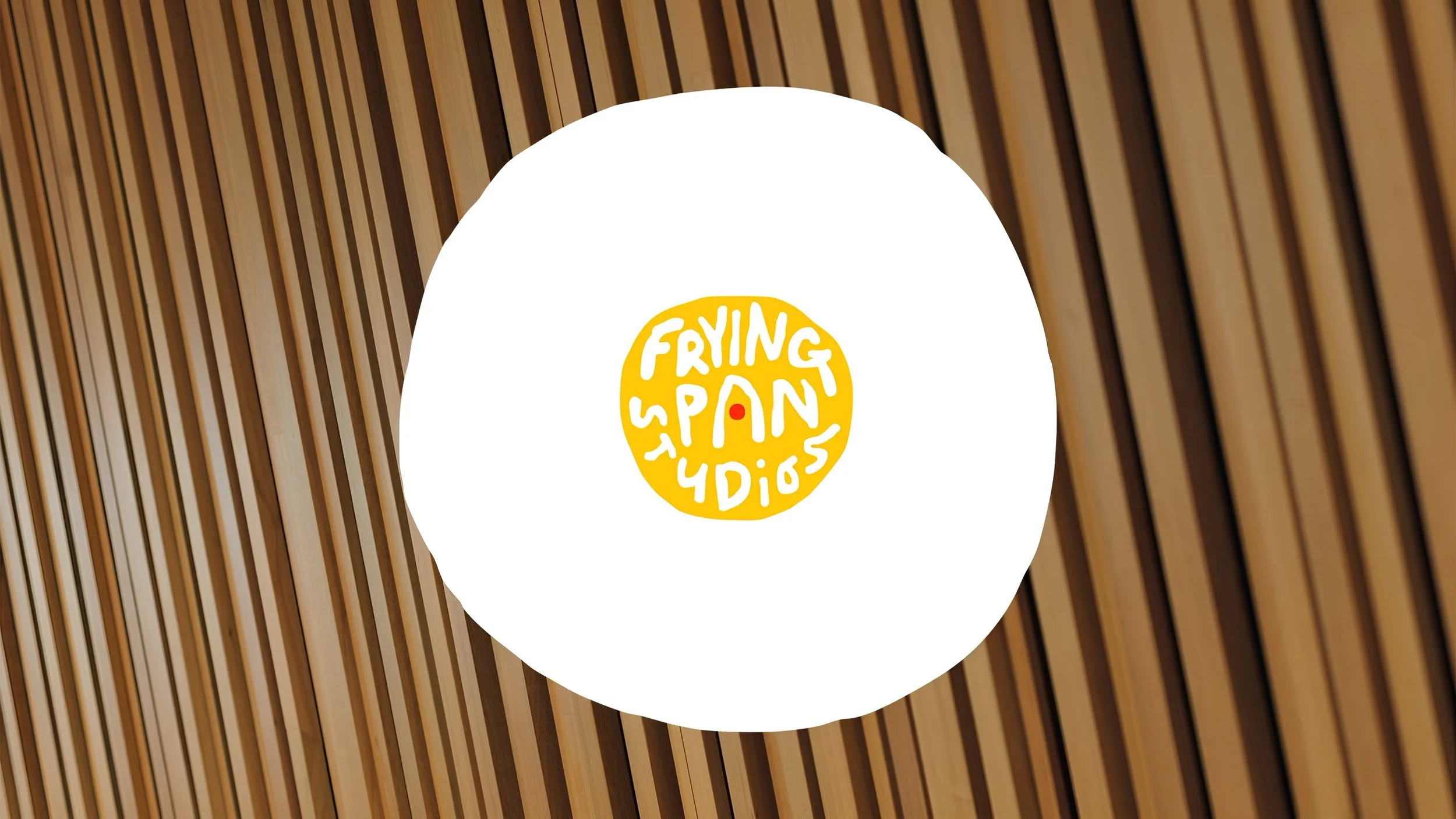 A round sign with the text 'Frying Pan 4 Dios' in yellow and white, mounted on a curved wooden wall.