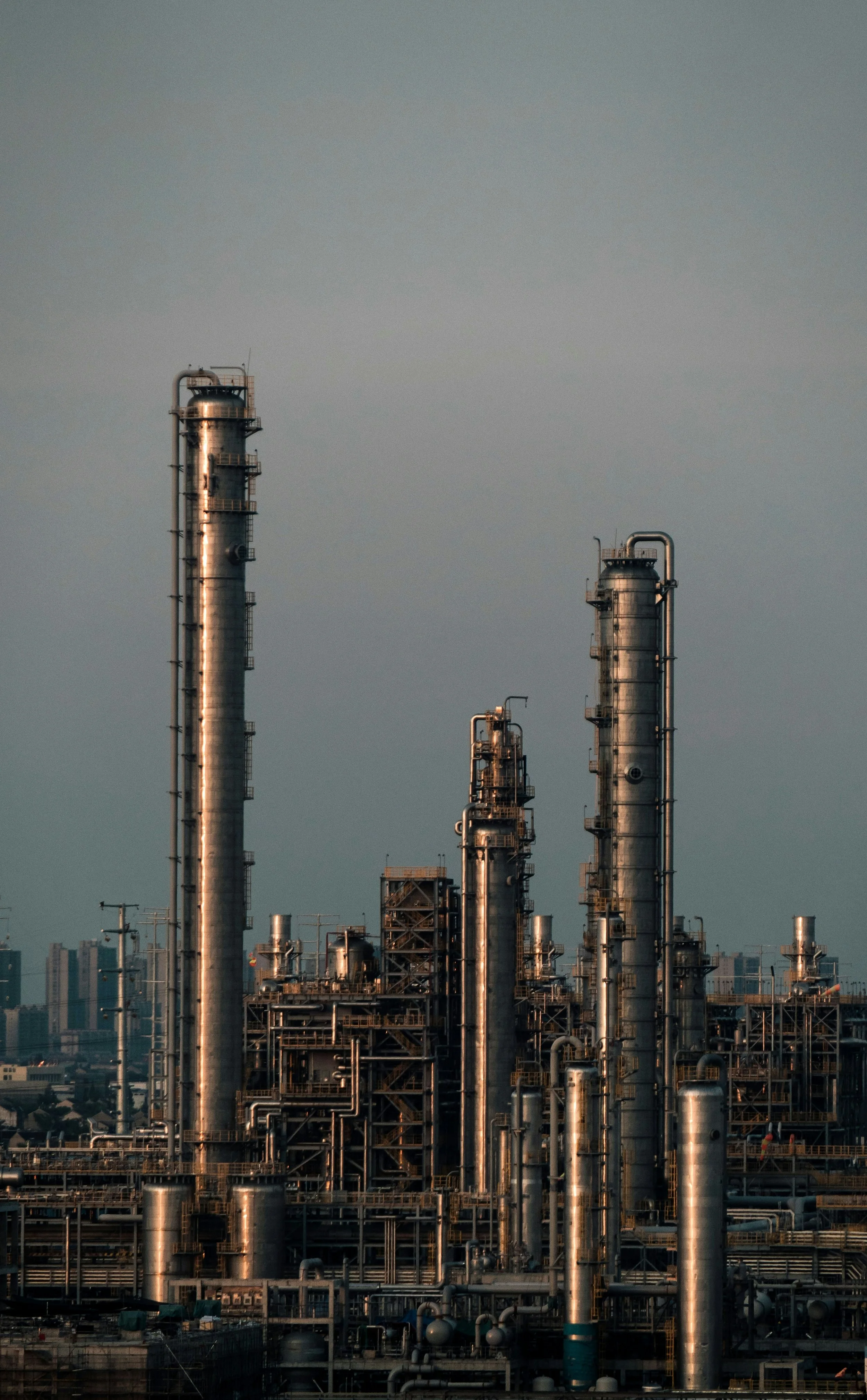 An industrial refinery with multiple tall smokestacks and complex piping structures.
